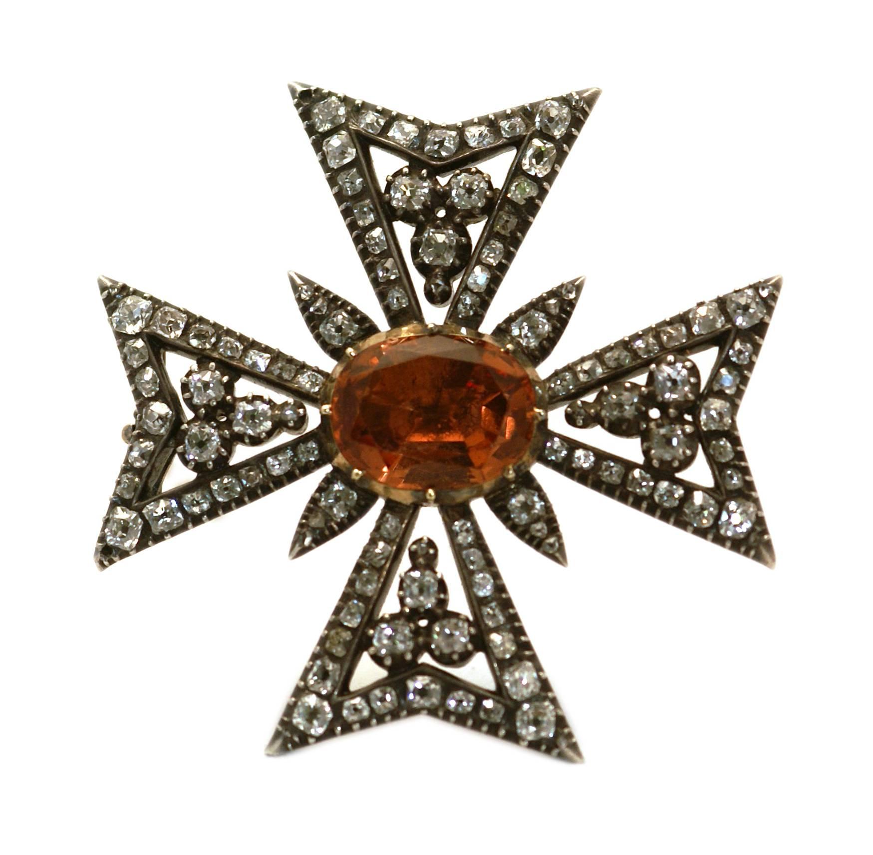 An exquisitely crafted antique Maltese Cross brooch, centering a fine Imperial Topaz, highlighted by old cut diamonds. Mounted in silver and gold. Circa 1880