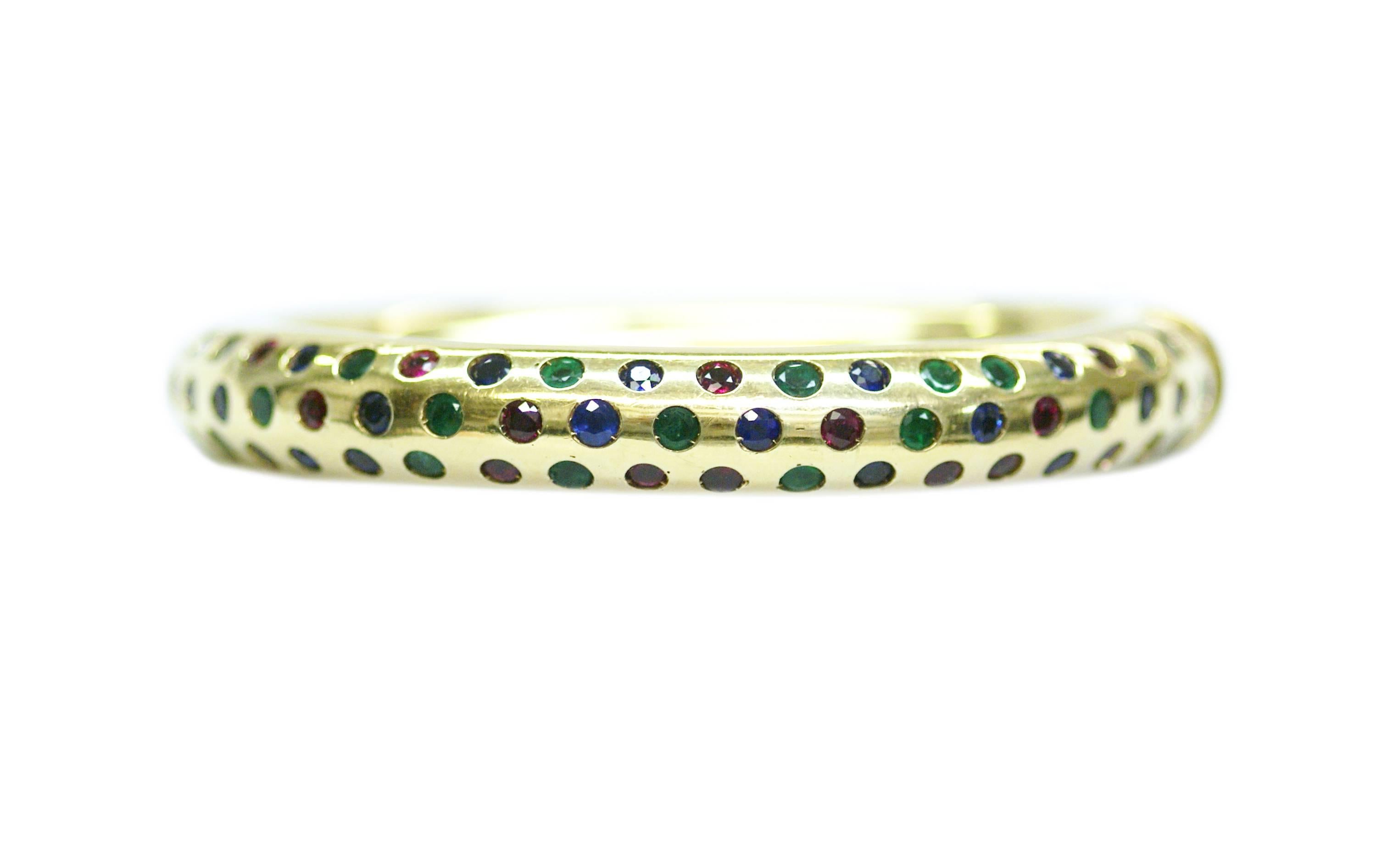 A finely crafted 18k gold bangle, highlighted by round cut sapphires, emeralds and rubies. Italy, circa 1975