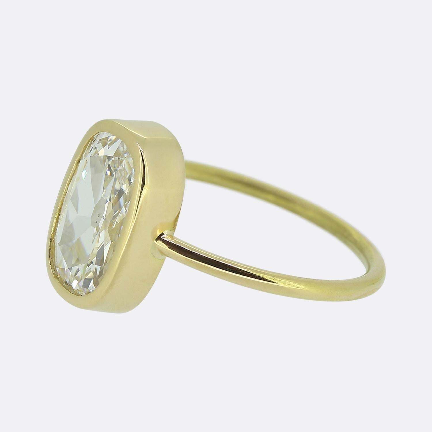 Here we have a striking diamond solitaire ring. This piece features an elongated old mine cut diamond at the centre of the face, showcasing a captivating bright white hue. This diamond sits alone in an elegant 18ct yellow gold bezel setting to