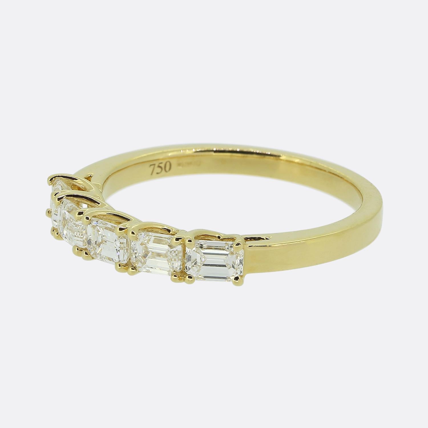 Ecco un affascinante anello con cinque pietre e diamanti. Questo pezzo vintage è stato realizzato in caldo oro giallo 18 carati e presenta una serie di diamanti bianchi taglio baguette incastonati in un design elegante e minimalista. I diamanti sono