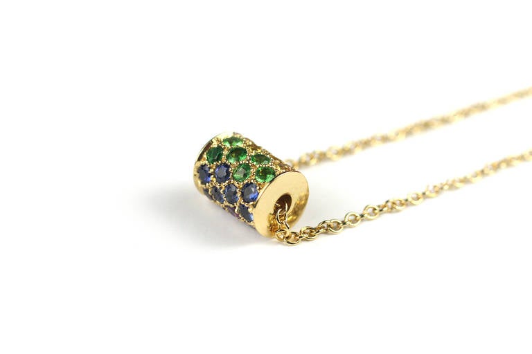 This beautiful and unique necklace has a multicolor gemstone barrel pendant that spins! Set in a rainbow color pattern, this pendant contains rubies, tsavorite, amethyst and blue, orange and yellow sapphires.

Designed and made in-house by Julius