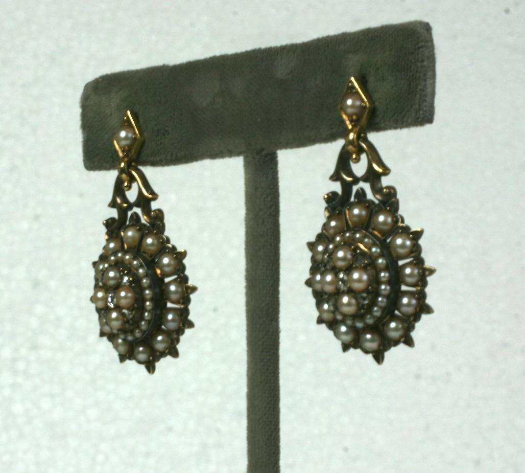 Lovely, high quality Victorian Seed Pearl Earrings with rose diamond accents. Heavy 14k gold quality construction with pierced star form design with natural, creamy half pearls set on varying levels.
The central motif swings from a scrolled bracket