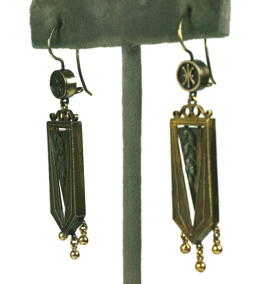 Victorian Earrings with articulated center motif which has an applied wheat motif in a shield shaped surround bordered in finely twisted wire. The earring has a pinkish gold cast on the interior dangle and a richer gold tone on the body.
3 small