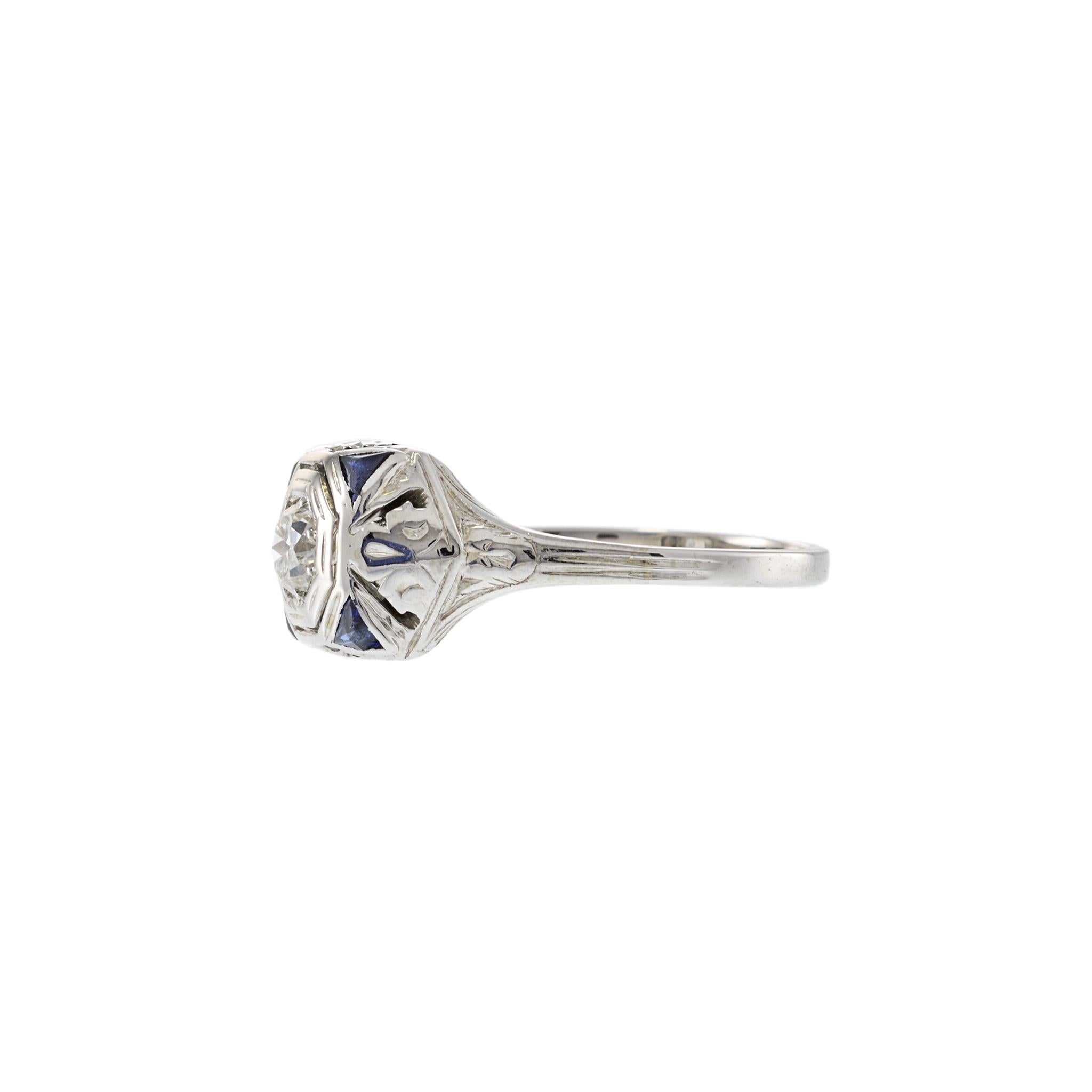 Questo anello antico, un pezzo notevole di artigianato dell'epoca edoardiana, presenta un diamante vecchio taglio europeo del peso di circa 0,36 carati (colore H, purezza VS2). Il diamante è splendidamente incorniciato da quattro zaffiri blu a