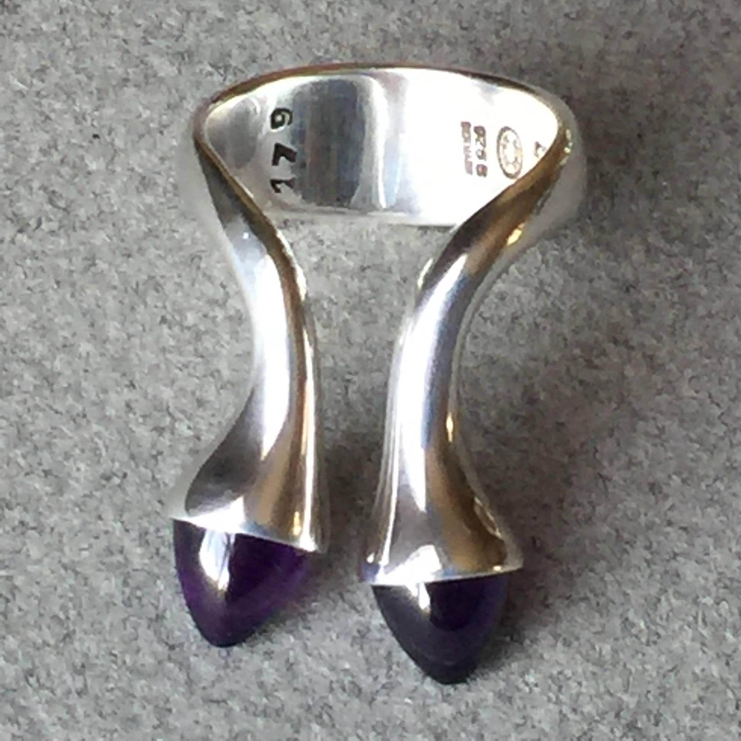 Georg Jensen Sterling Silver Ring No. 179 by Bent Gabrielsen with pair of amethyst bullet shaped cabochons.

Unique modernist design with two protruding bullet shaped cabochons.

Complimentary gift box and FREE shipping included.

About the