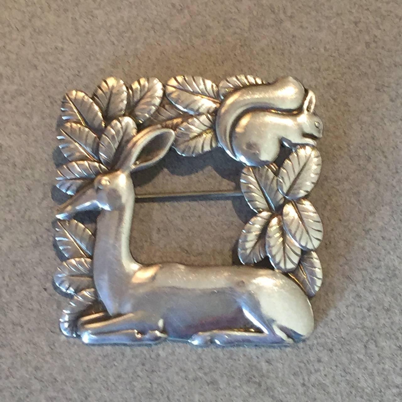 Intricately detailed, open-squared brooch featuring a deer resting before a squirrel in foliage. Very well made with gorgeous patina.