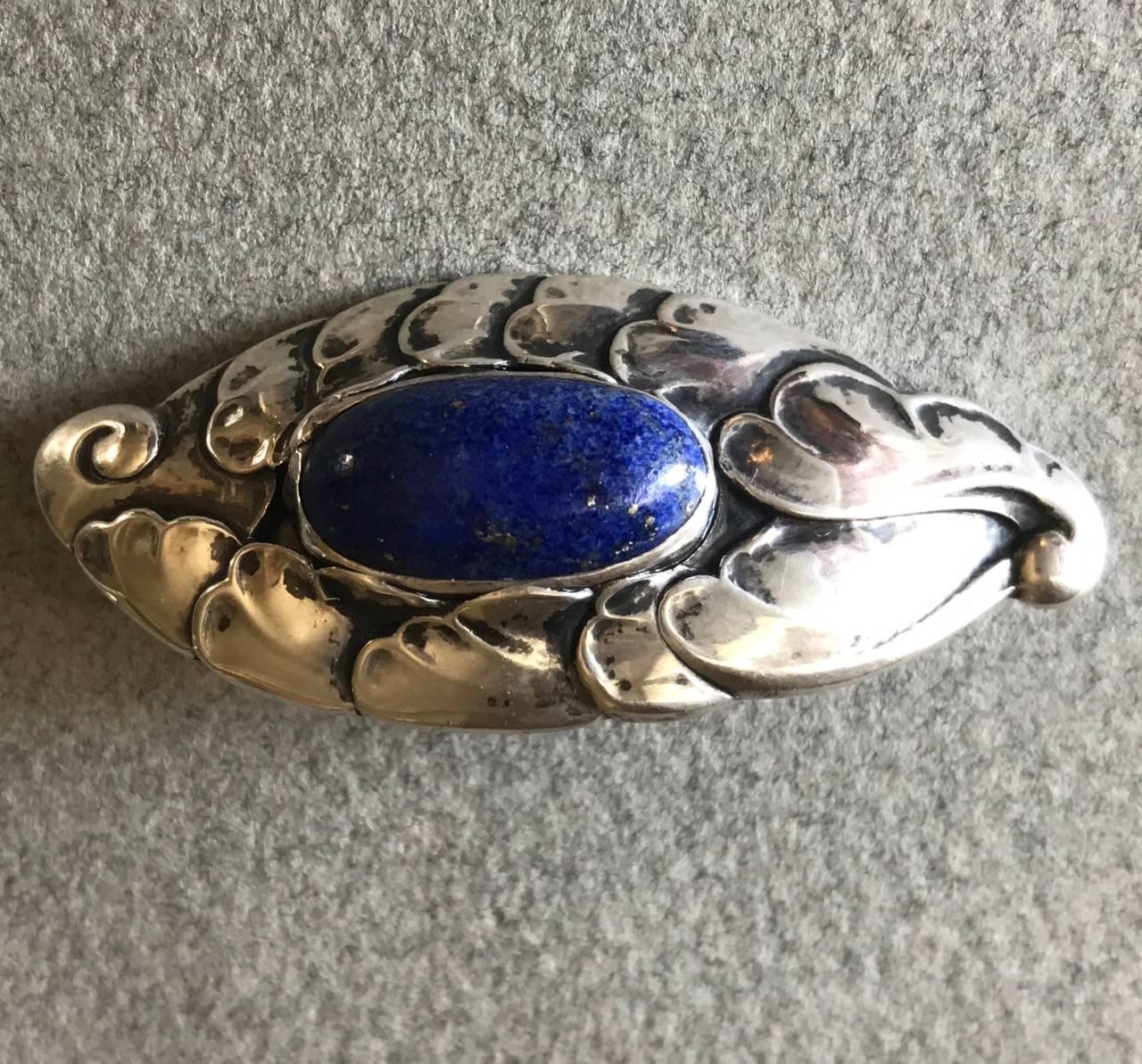 Georg Jensen 830 Silver Brooch No. 168 With Lapis Lazuli.

Almond shaped brooch with bright lapis lazuli stone and foliate detail. Trombone clasp. Very good condition. Rarely seen.

Early hallmarks indicate 1919-1927.

Discreetly engraved initials.
