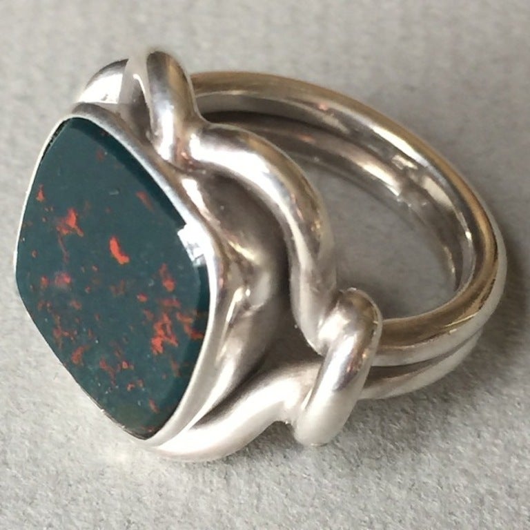 Georg Jensen Sterling Silver Ring No. 27A with Bloodstone

Beautifully handmade, classic design with square bloodstone of exceptional quality. Rare bloodstone that is deep dark green with red flecks that give the stone its name. Intertwined thick,
