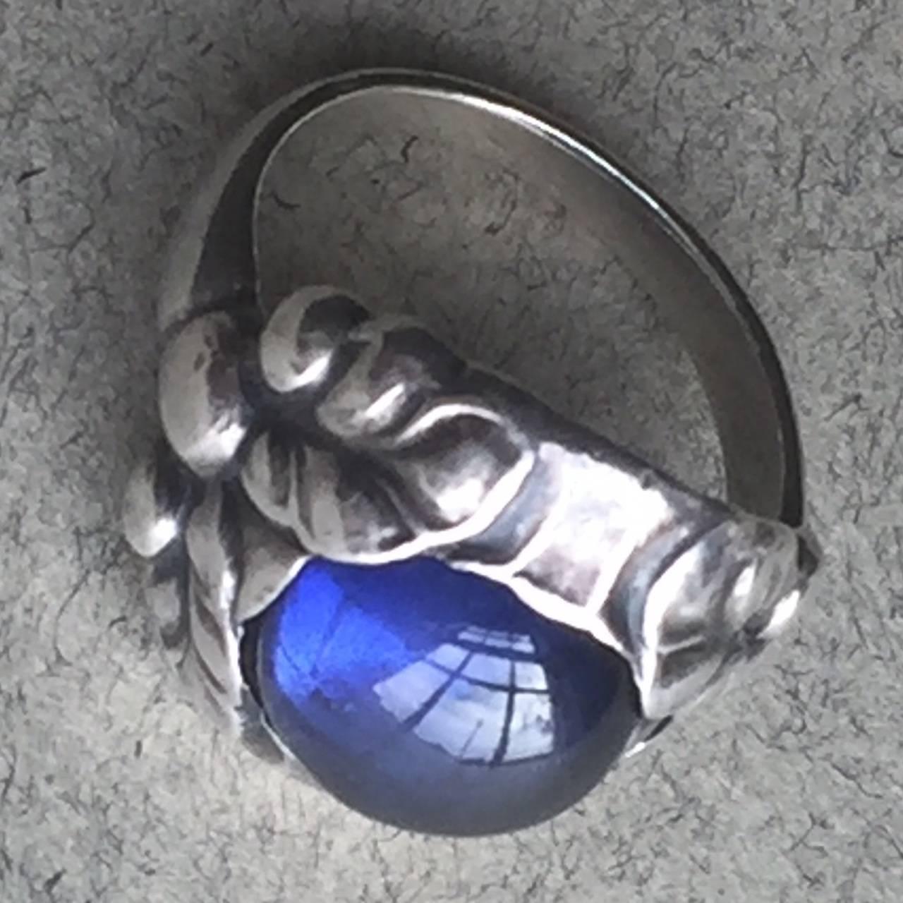 Georg Jensen Sterling Silver Ring No. 11b with Synthetic Sapphire.

Art nouveau sterling silver ring that features a vibrant blue synthetic sapphire gemstone in the center of a leaf pattern setting. 

Size 6 ring in excellent condition with