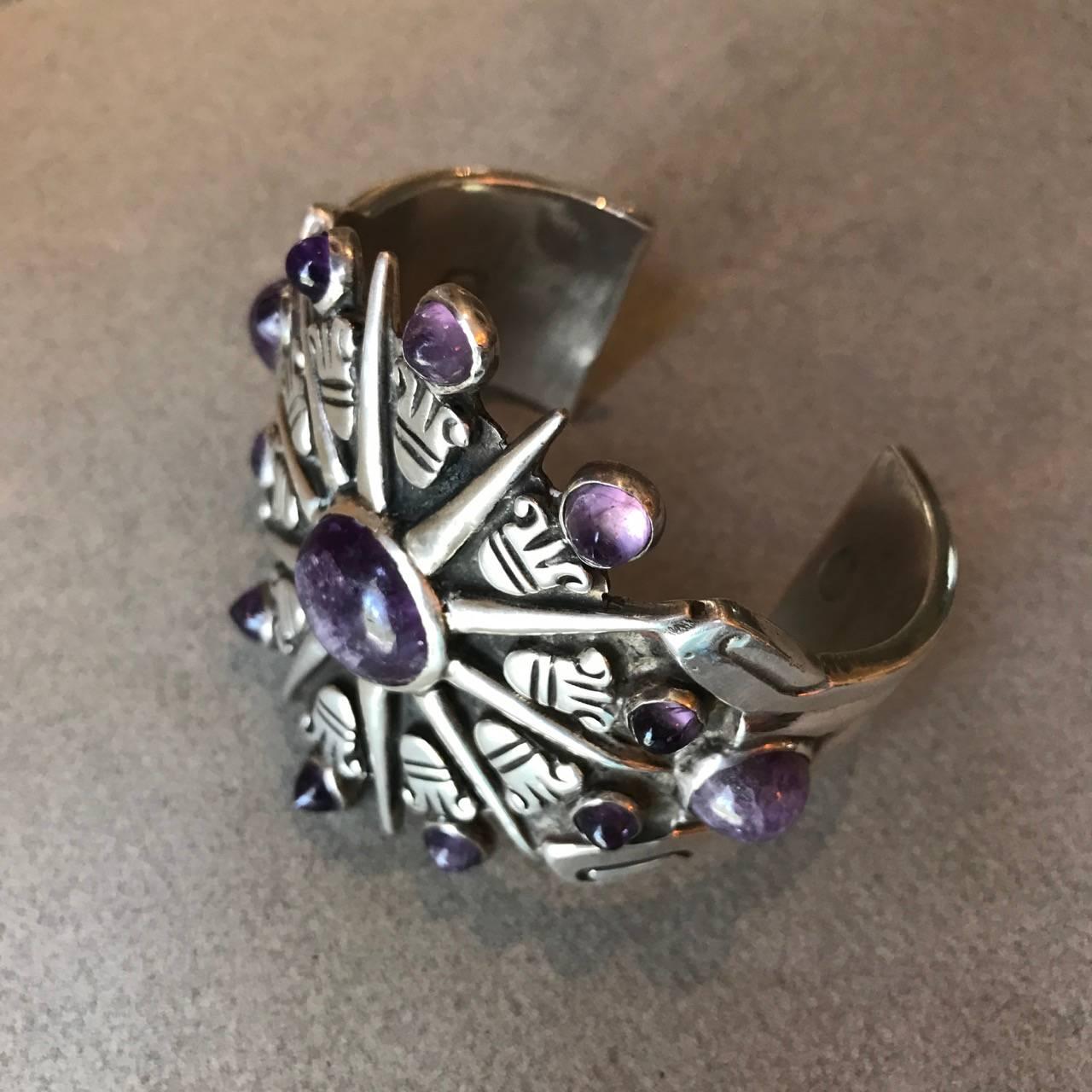 William Spratling Sterling Silver Aztec Sun Cuff with Amethyst

A superb piece by Taxco master William Spratling, this cuff bracelet is truly a work of art. It is solidly constructed with high relief of oxidized sterling silver with 13 bezel set