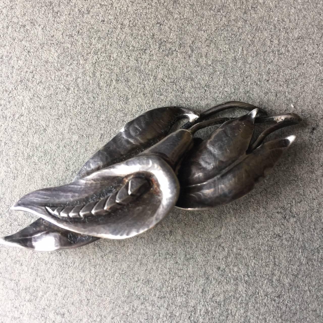 Peer Smed Sterling Silver Calla Lily Brooch.

Signed and hallmarked handwrought Peer Smed Sterling Silver Brooch. This  wonderful Calla Lily with a long, curving stamen resting against several leafs and stems. Very dimensional and well made. 