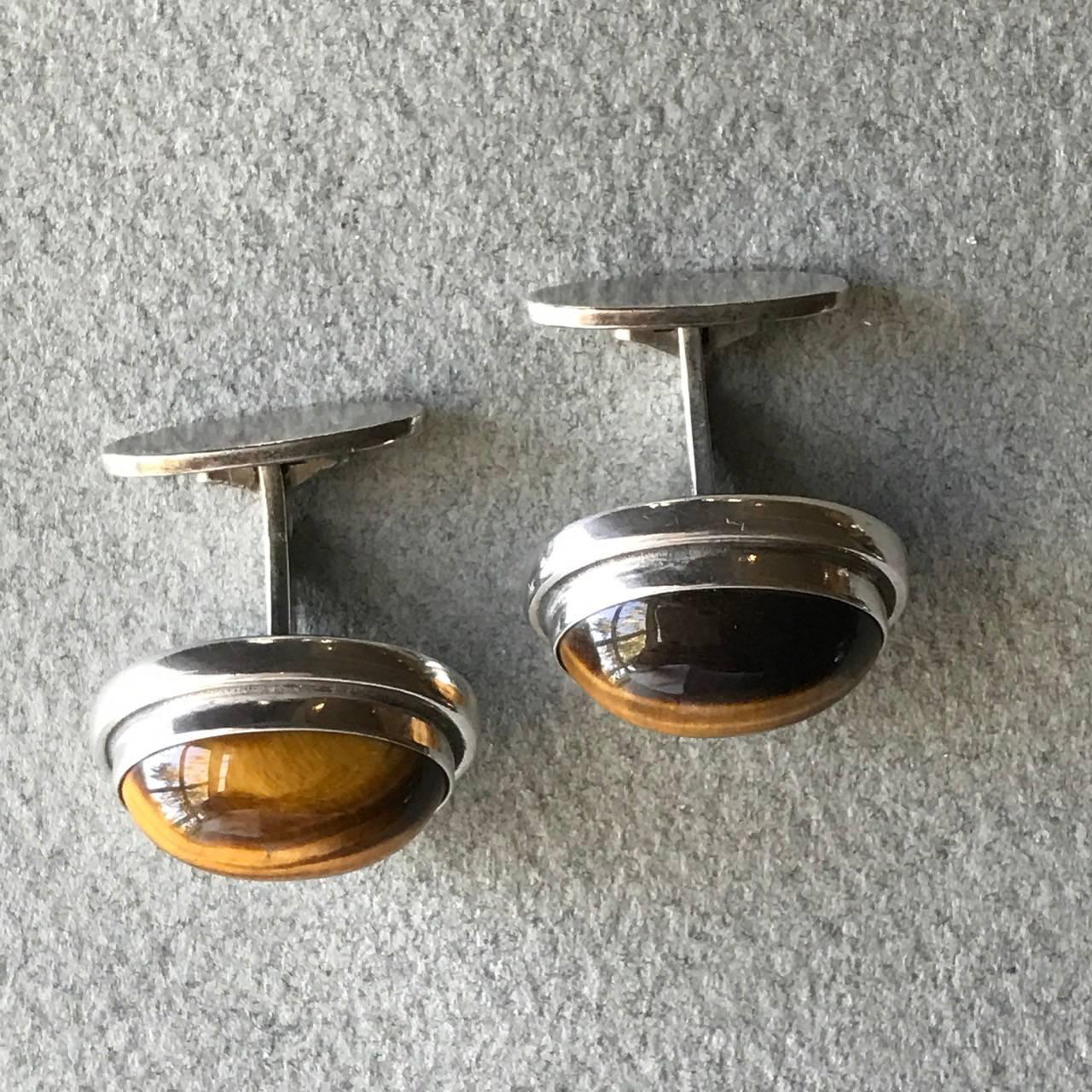 Georg Jensen Sterling Silver and Tiger Eye Cufflinks, No. 44A By Harald Nielsen

An uncommon pair of oval sterling silver cufflinks set with Tiger Eye cabochon. The pair comes in their original Jensen box, circa 1951.