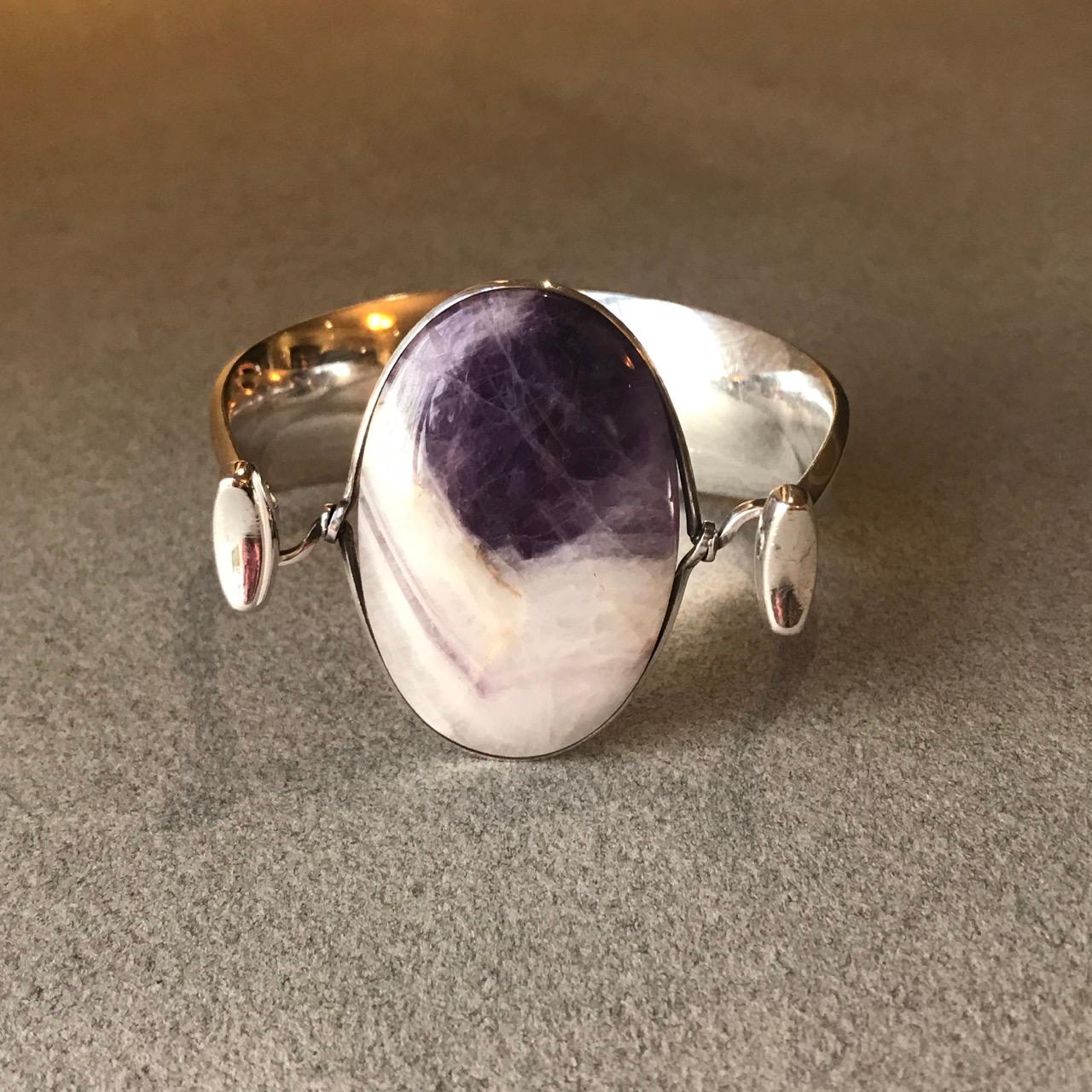 Georg Jensen Sterling SIlver and amethyst Bracelet, No. 203 by Vivianna Torun Bulow-Hube.

Fantastic example of a timeless design. Stone is amethyst in “matrix” showing the beautiful variegation of color.  This piece dates from the 1970's and comes