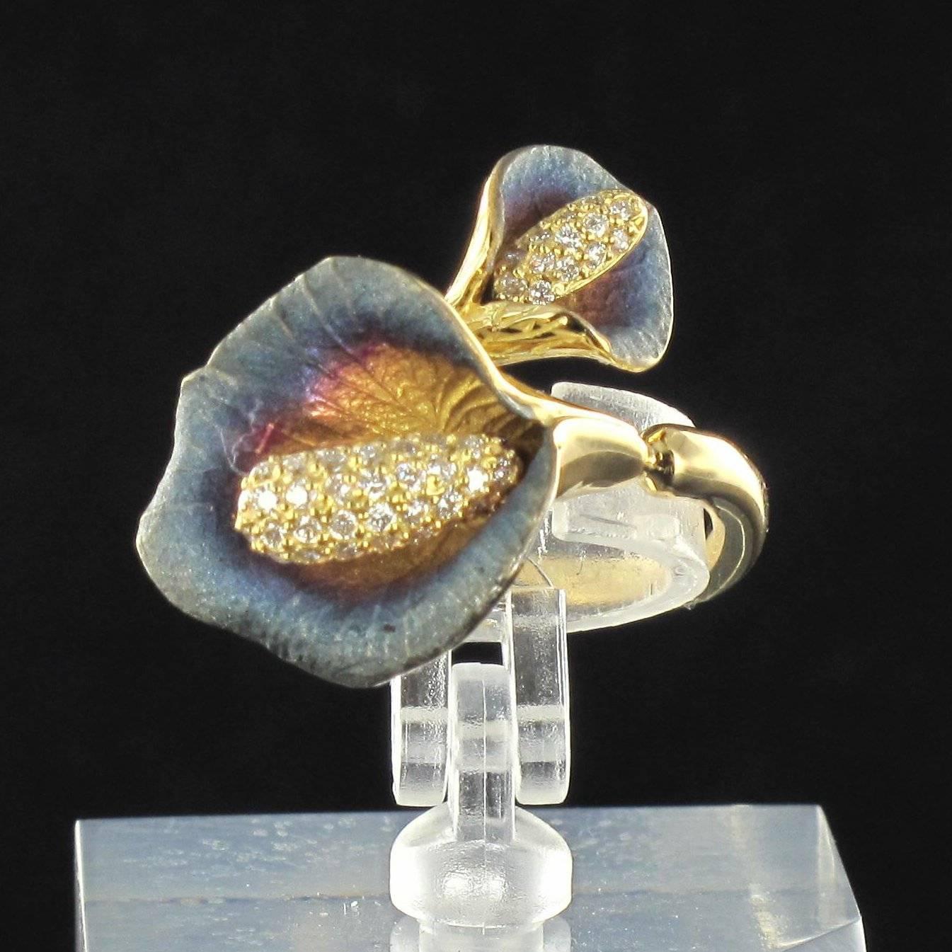 Ring in 18K Yellow gold.

Consisting of two arum lily flowers with pink enamel hearts fading to blue at the edges, the pistils are of diamonds. One lily is larger than the other; they meet at the top of the finger. 

Length: 5 cm, width: 2 cm