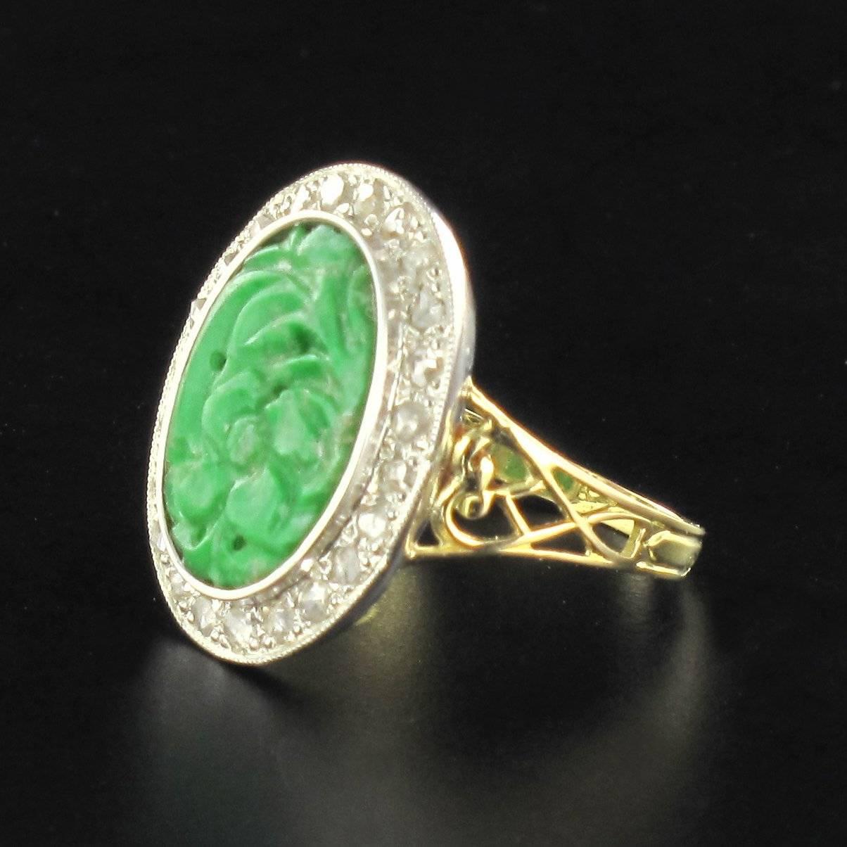 Ring in 18K yellow gold, and silver, mixed hallmark.
The head of the ring is dominated by a flower engraved oval jade centre surrounded by rose cut diamonds. The shoulders are attractively decorated with a lace pattern leading into the ring band.