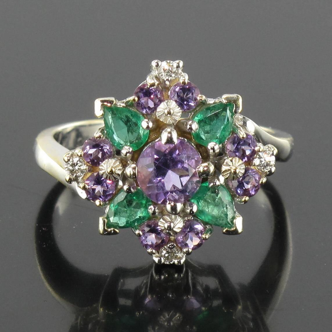 Ring in 18 carat white gold. 

This striking antique white gold ring is set with a central round amethyst surrounded by 4 marquise cut emeralds, 8 round amethysts and 4 brilliant cut diamonds set at the compass points. 

Height: 1.57 cm, width: