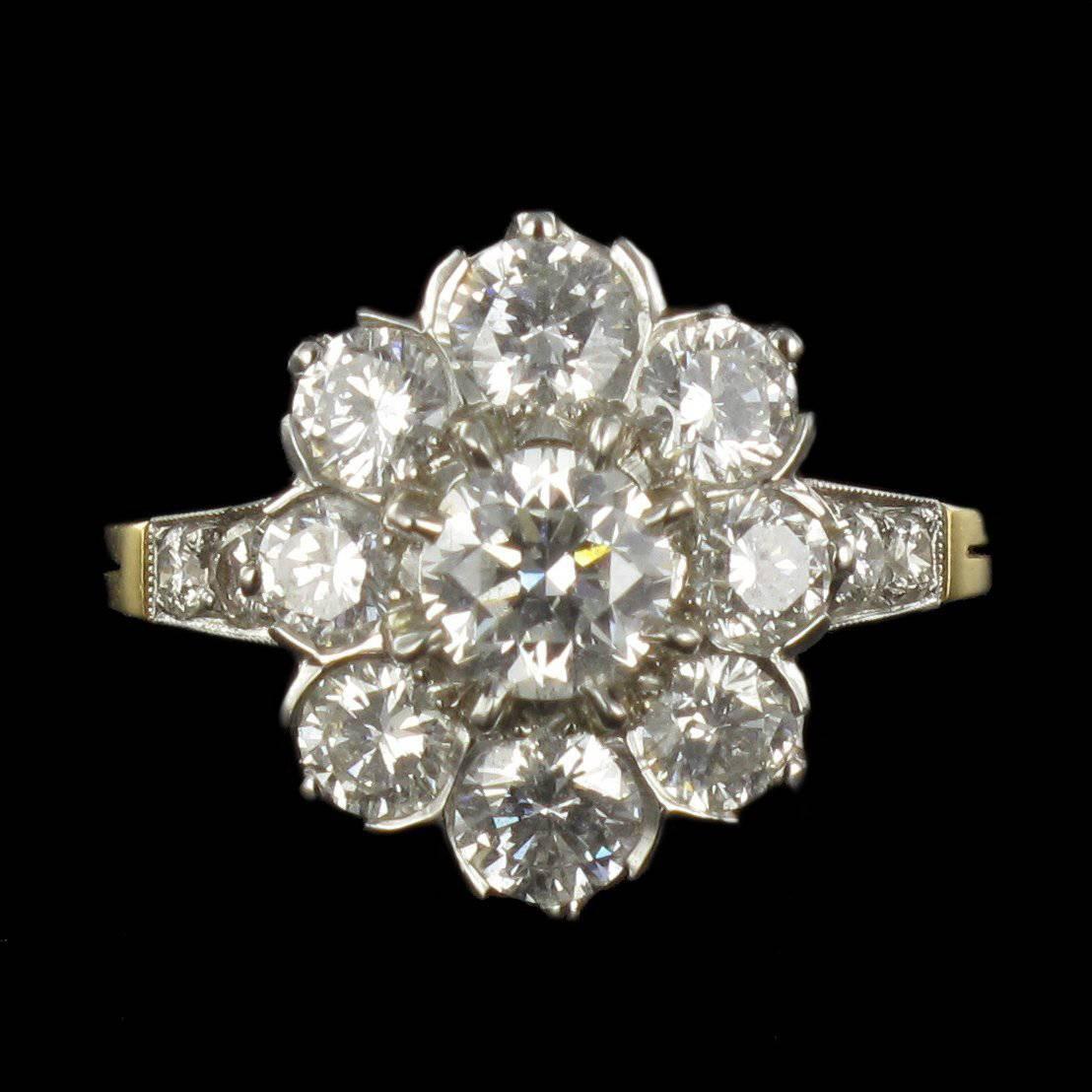 Ring in platinium and 18 carat yellow gold, dog and eagle heads hallmarks. 

This delightful Daisy style ring features a claw set central brilliant cut diamond surrounded by 8 other claw set diamonds. At each shoulder, at the beginning of the ring