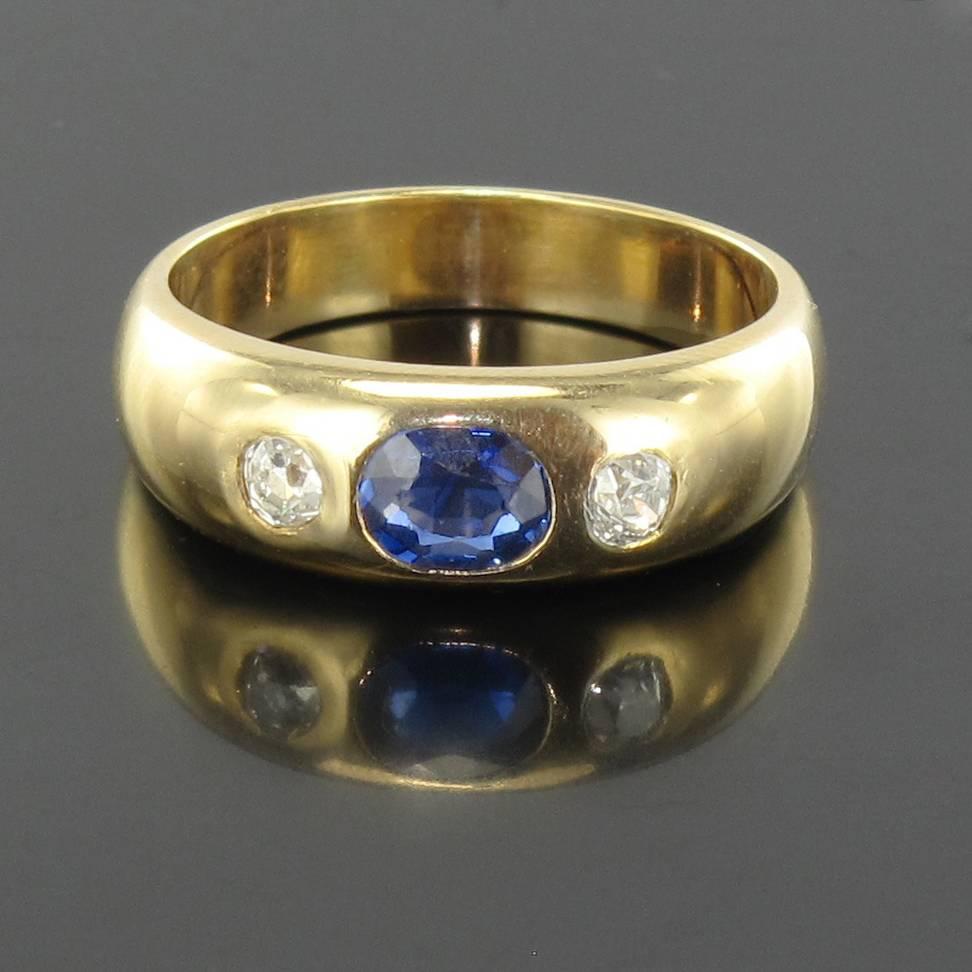 Ring in 18 carat yellow gold, eagle head hallmark. 

This ring is bezel set with an oval blue sapphire shouldered by 2 antique brilliant cut diamonds. 

Ring width at the base: 4.2 mm. Height: 6.5 mm.
Sapphire Weight: 0.50 carat