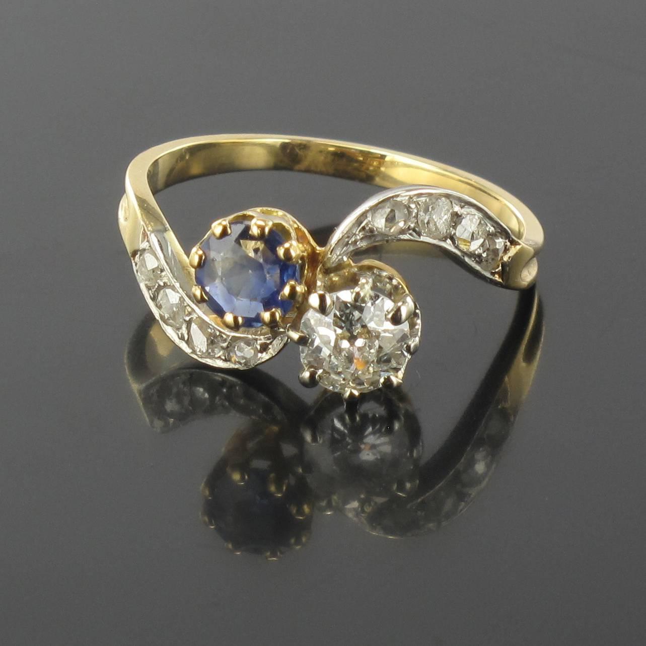 Ring in 18 carat yellow gold, eagle head hallmark. 

This Lovers ring is claw set with a brilliant cut diamond and a round blue sapphire. The beginning of the ring band at each side is set with a curve of 4 rose cut diamonds.

Weight of the
