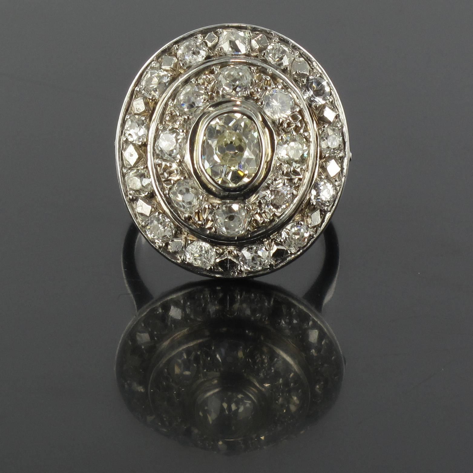 Ring in 18 carat white gold, eagle head hallmark. 

This luminous oval antique diamond ring is bezel set with a central cushion cut diamond within a double halo of antique cut diamonds. The ring bed is openwork decorated with golden strands. 