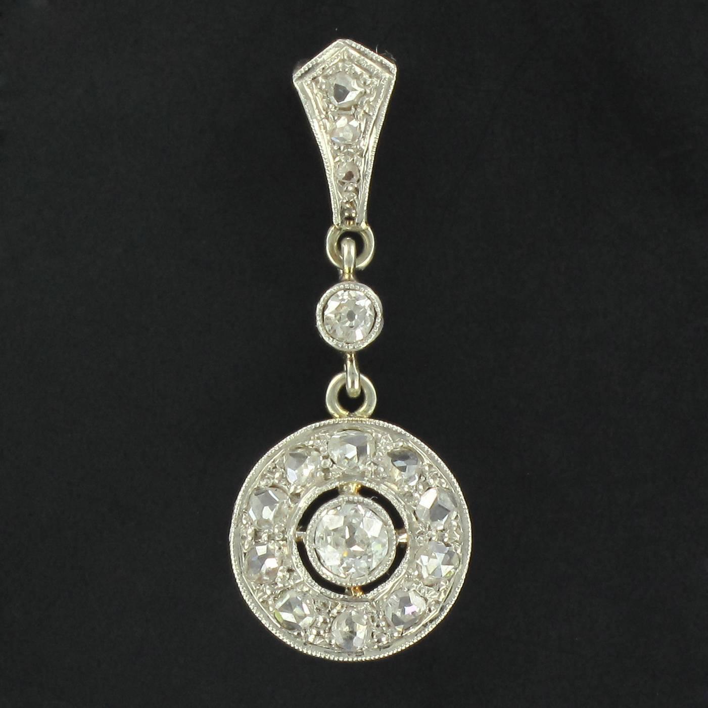 18 carat white gold pendant. 

This splendid round openwork Art Deco pendant features a central bezel set antique brilliant cut diamond surrounded by rose cut diamonds. This round motif is held by a bail set with an ornamented column of 3 rose cut