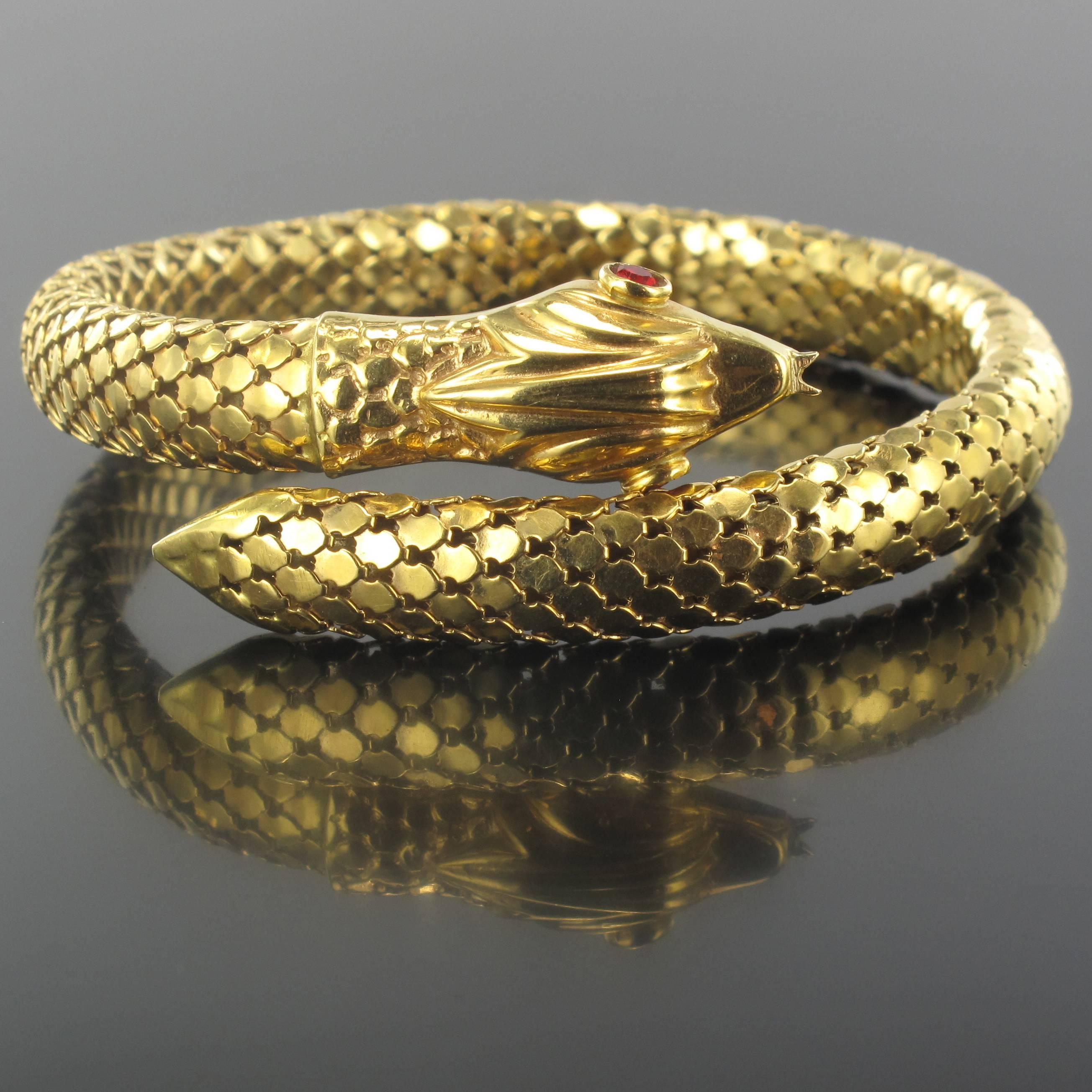 Bracelet in 18 carat yellow gold. 

Portraying a snake, this bracelet features golden scales across its entire surface. The head is set with 2 red gems for eyes. The bracelet is flexible ensuring that anyone can wear it, regardless of their wrist