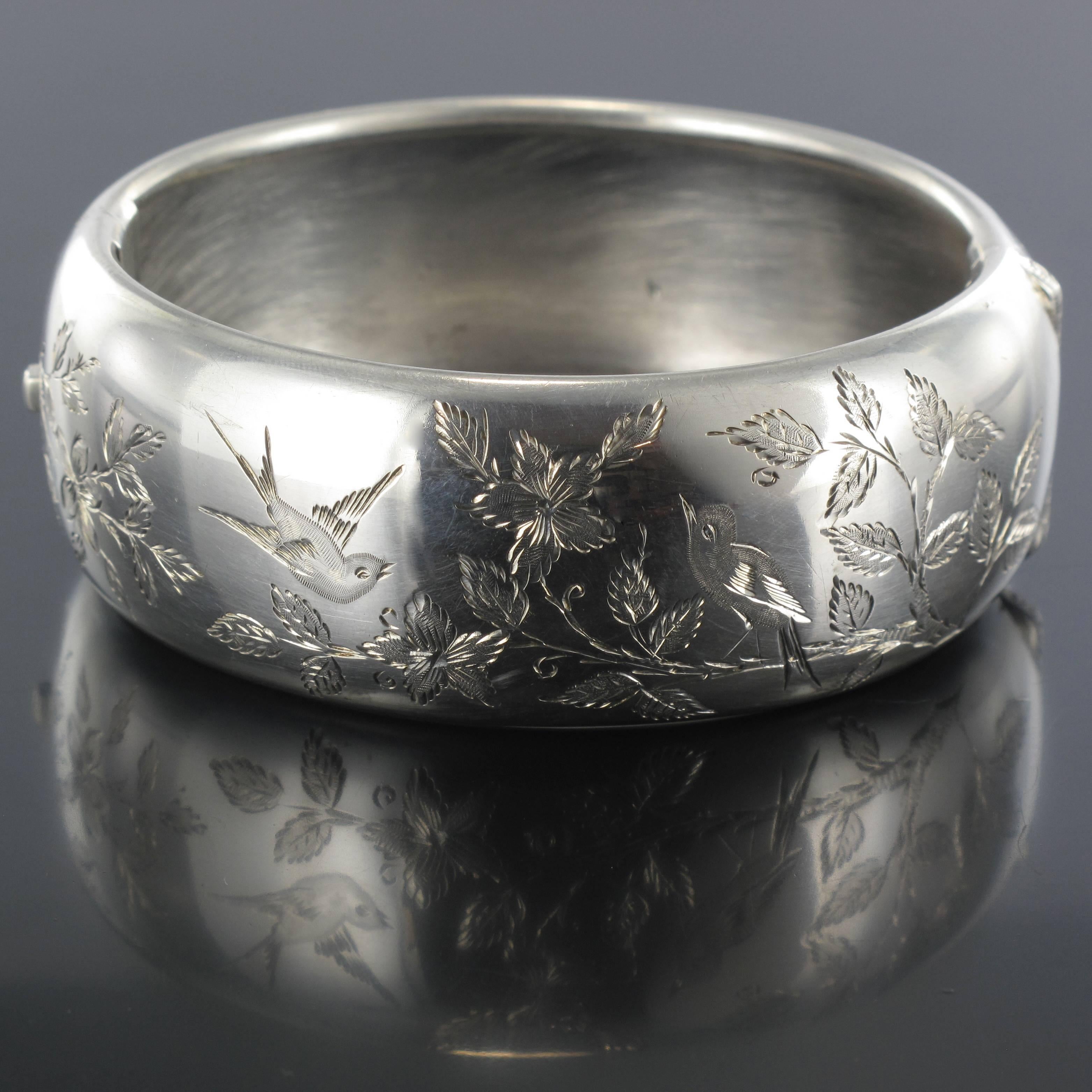 Bracelet en argent. 

Ce bracelet bangle en argent ovale et arrondi est finement gravé d'une scène printanière d'oiseaux perchés sur des branches fleuries. Il possède un fermoir à charnière. 

Circonférence du poignet : 22.9 cm:: largeur 3::9 cm.