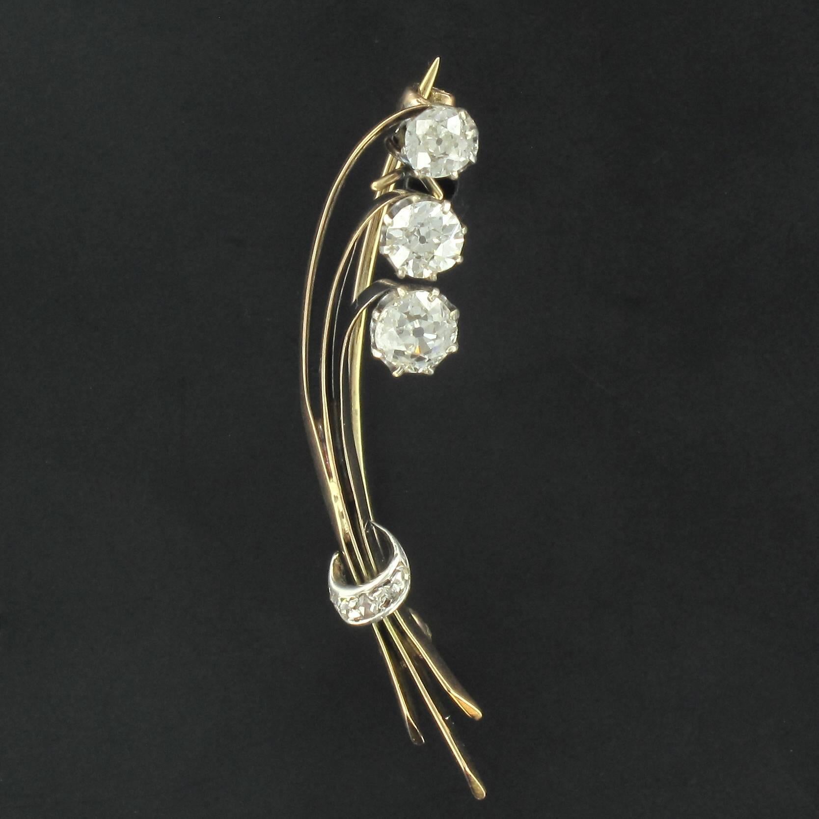 Brooch in 18 carat yellow gold, eagle head hallmark and silver.  

This brooch in the form of a bunch of flowers is claw set with 3 brilliant cut diamonds. The stems are held at the base by a band set with diamonds. The clasp is a pin with a
