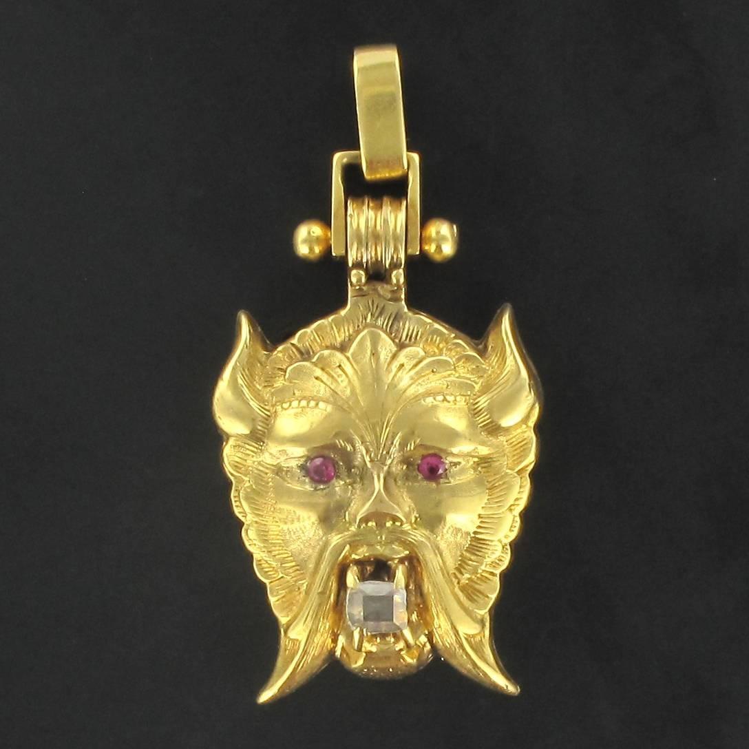 Locket pendant in 18 carat yellow gold, eagle head hallmark.

This particularly original pendant features an engraved Chimera head with small rubies for eyes holding an antique cushion cut diamond in its mouth. The pendant can be opened with a