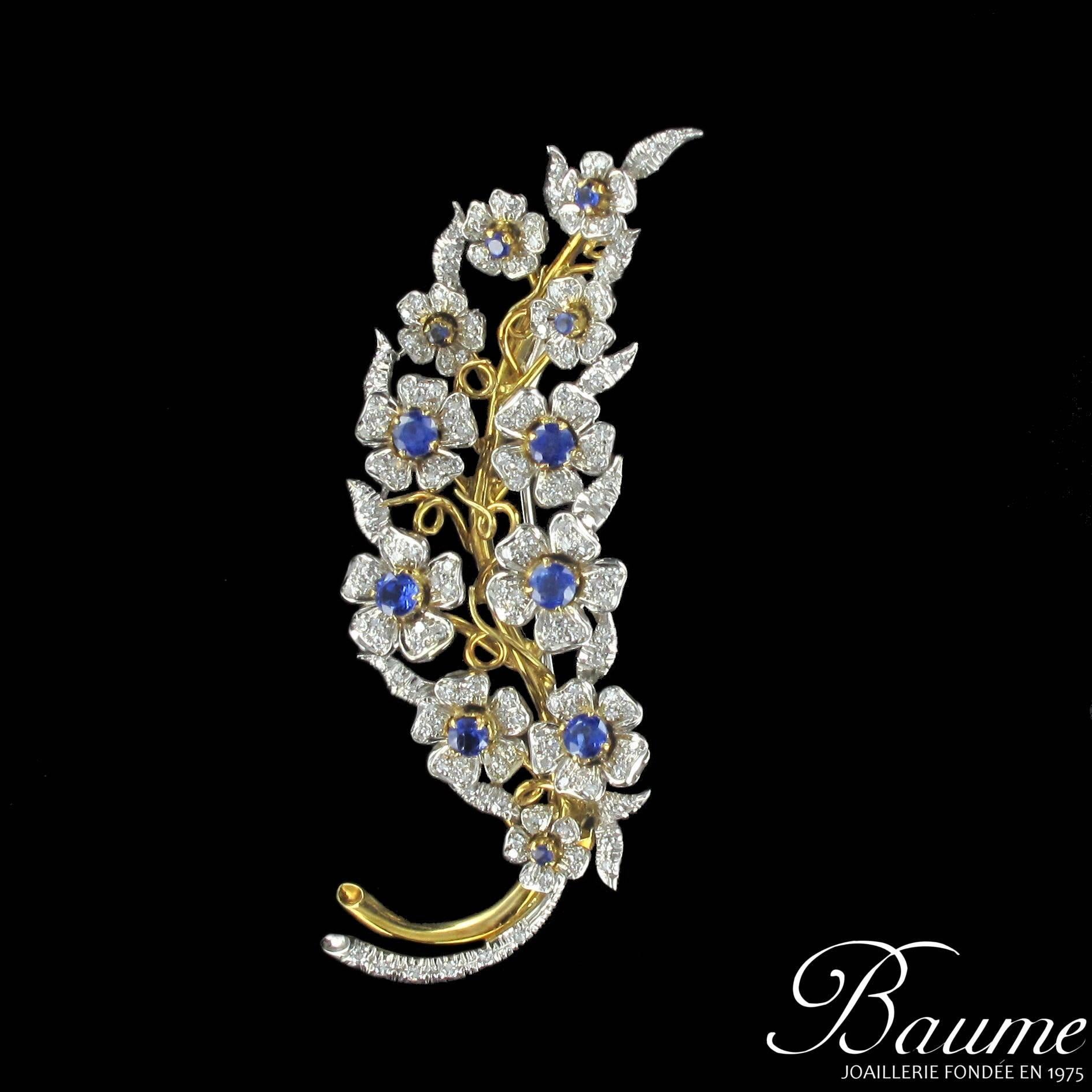 Brooch in 18 carats white and yellow gold.

This sapphire and diamond brooch in the form of an openwork branch features numerous flowers with claw set round blue sapphires at their centre and diamonds set into the petals. This antique brooch has