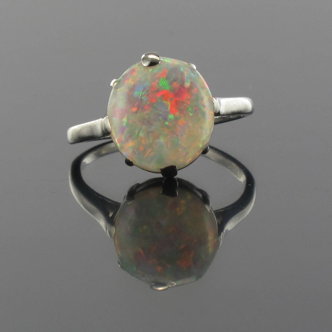 Platinum ring, dog's head hallmark.

This stunning ring is claw set with a natural opal cabochon that is slightly oval in shape. The ring bed is openwork thereby allowing light to enter and illuminate the opal. 

Total weight of the opal: 1.70