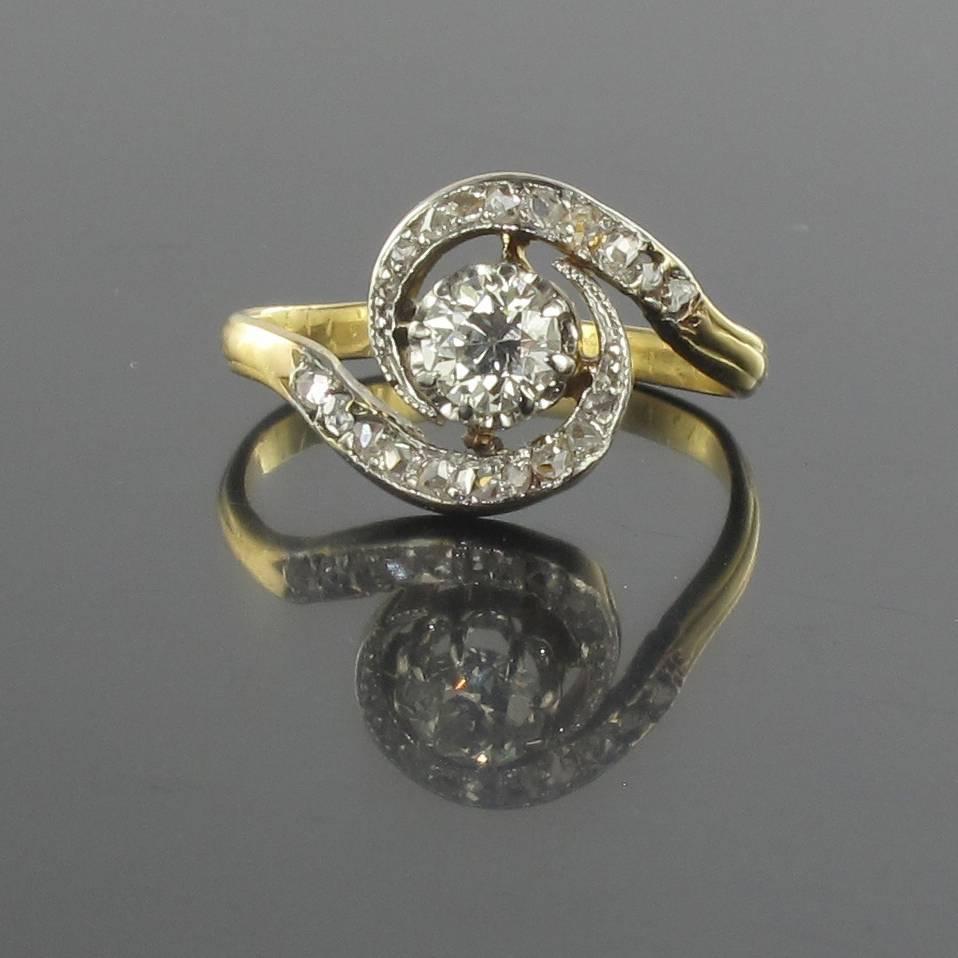 Ring in platinium and 18 carat yellow gold, eagle head hallmark. 

This radiant antique ring is claw set with whirls of rose cut diamonds and a beautiful central brilliant cut diamond. 

Weight of the main diamond: about 0.36 carat.
Height: 12
