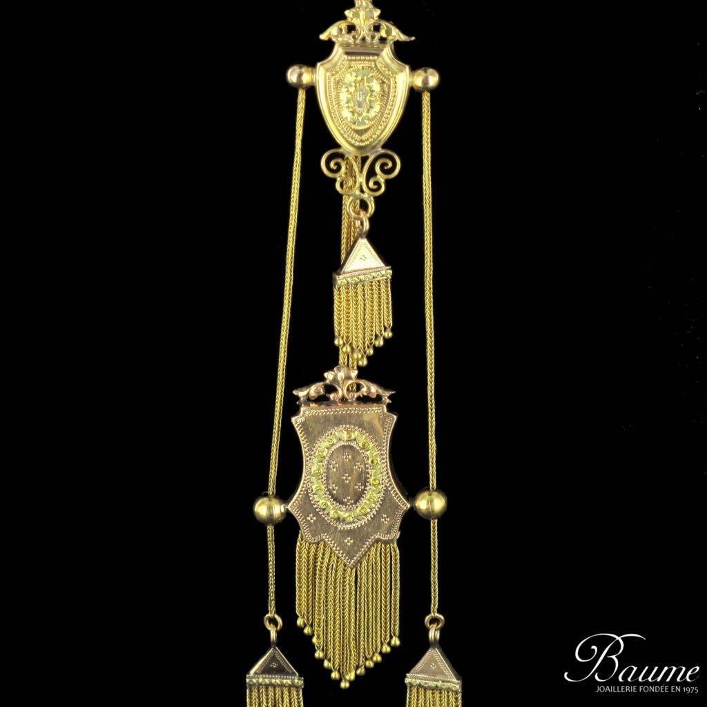 Necklace in 18 carat yellow - rose - green golds, horse head hallmark. 

Compose of a chain column that terminates with numerous engraved motifs completed by a golden fringe; the largest motif features a sliding design. This matinee necklace has a