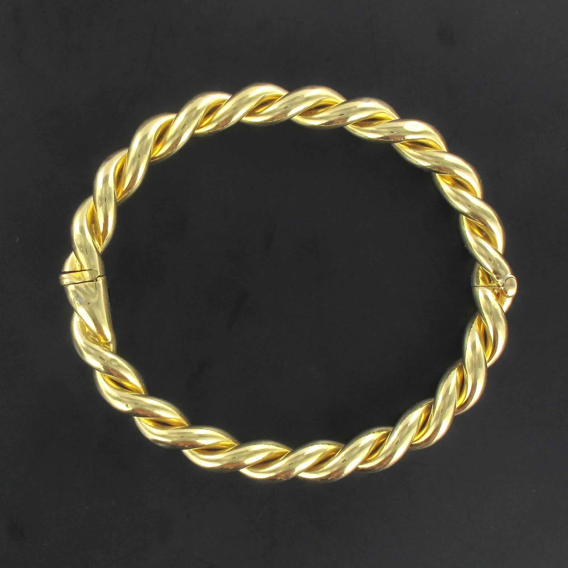 Bracelet in 18 carat yellow gold. 

This stunning antique round bangle bracelet is composed of twisted gold. The clasp is in the form of a hinge with a safety clip. 

Interior dimensions: 6.5 cm x 5.6 cm, width 7.4 mm. 
Circumference: 24.8