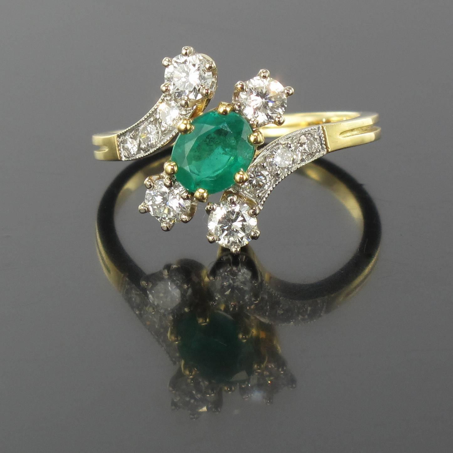 Ring in 18 carat yellow gold, eagle head hallmark and platinium, dog head hallmark.

This ring is diagonally claw set with an oval emerald between two diamonds. At each side another diamond and a curve of three other smaller diamonds forms the