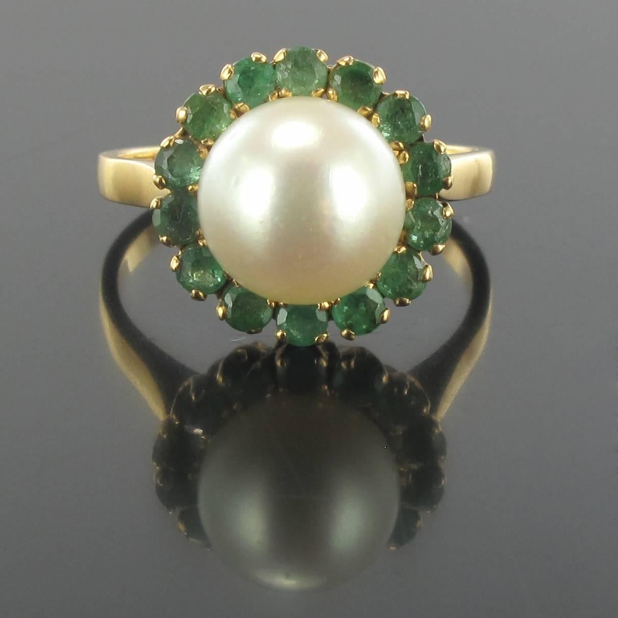 Ring in 18 carat yellow gold, eagle head hallmark. 
Round, it is set with a round white oriental pearl surrounded by 14 round emeralds set in claws. The basket make golden sons.
Total weight of emeralds: about 0.60 carat.
Pearl diameter: 9 / 9.5