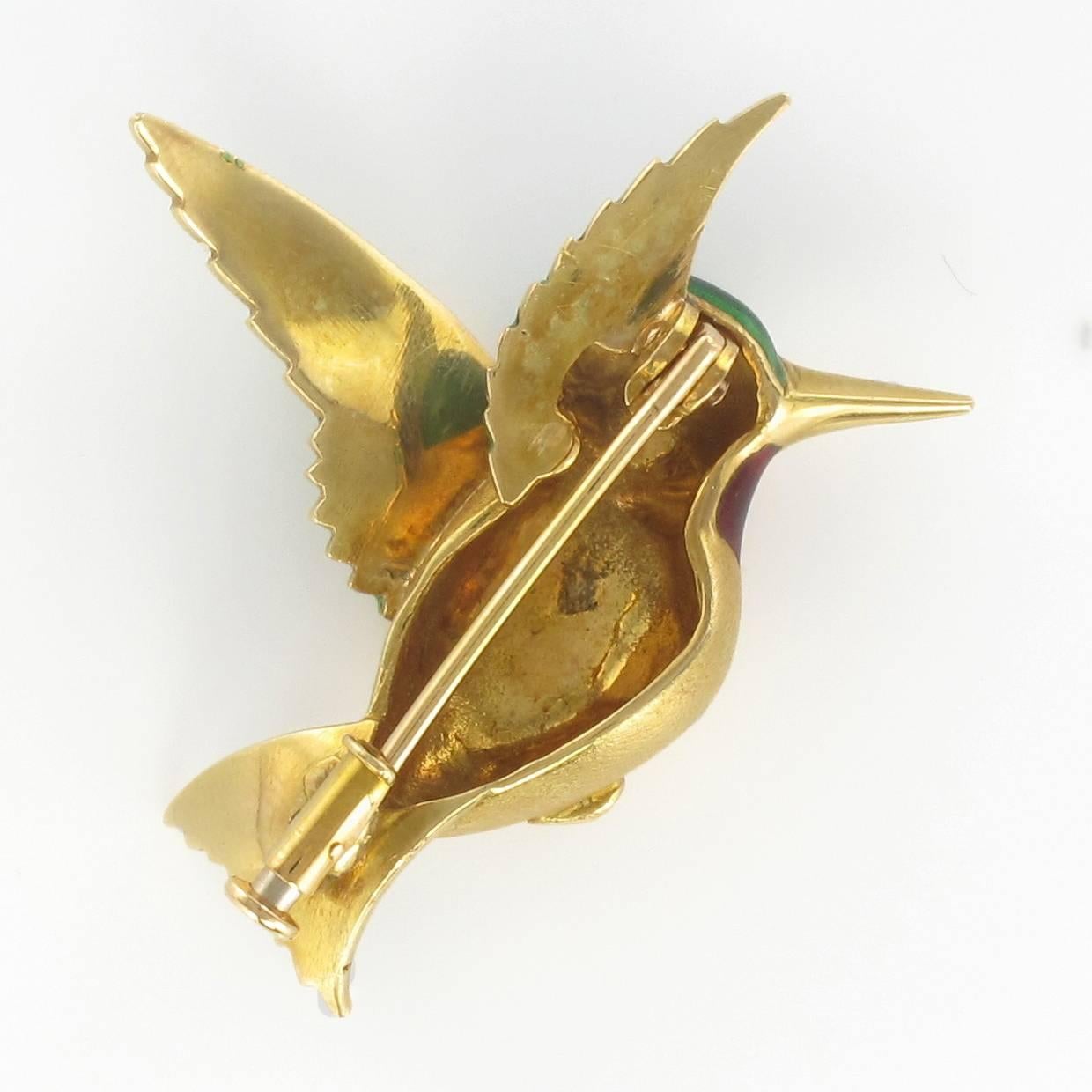 Brooch in 18 carat yellow gold, eagle head hallmark. 

This splendid brooch displays a humming bird in flight. The body is gold, the wing and tail feathers are in green enamel, the neck and the eye are red enamel. The clasp of this brooch is a pin