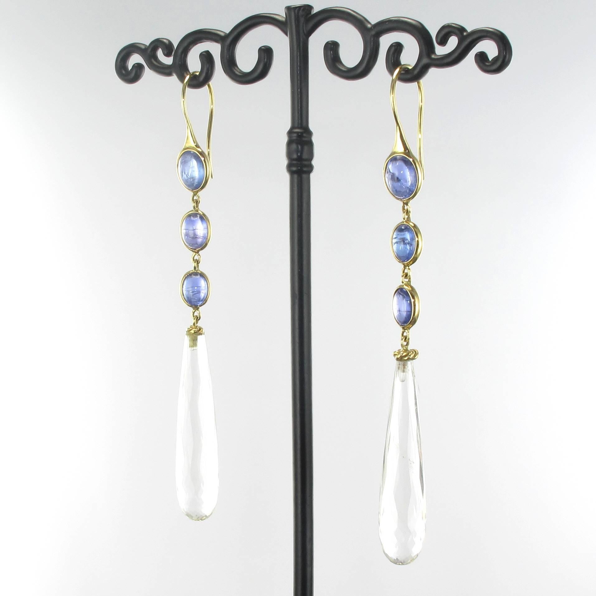 Earrings in 18 carat yellow gold. 

Long dangle earrings each composed of a column of 3 bezel set oval tanzanite cabochons with a suspended radiant clear rock crystal teardrop. These tanzanite dangle earrings feature gooseneck clasps. 

Total