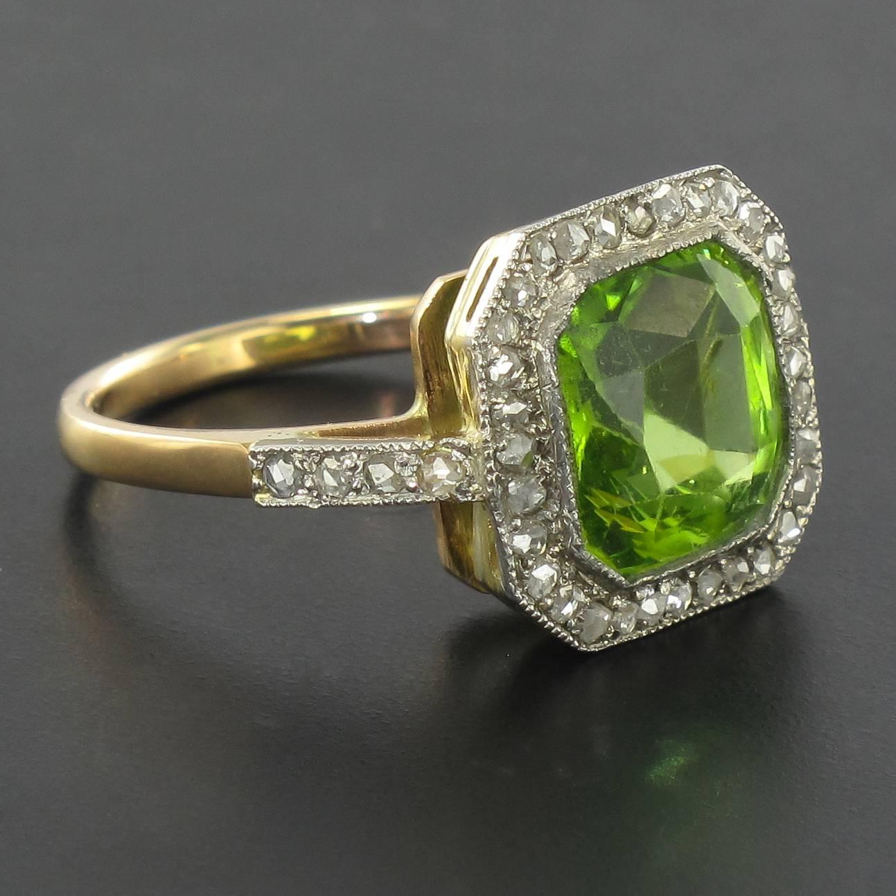 Ring in 18 carat yellow gold. 

An elegant antique ring that is bezel set with an emerald cut faceted Peridot surrounded by rose cut diamonds in a beaded bezel setting. The beginning of the ring band is set on each side with a line of small rose