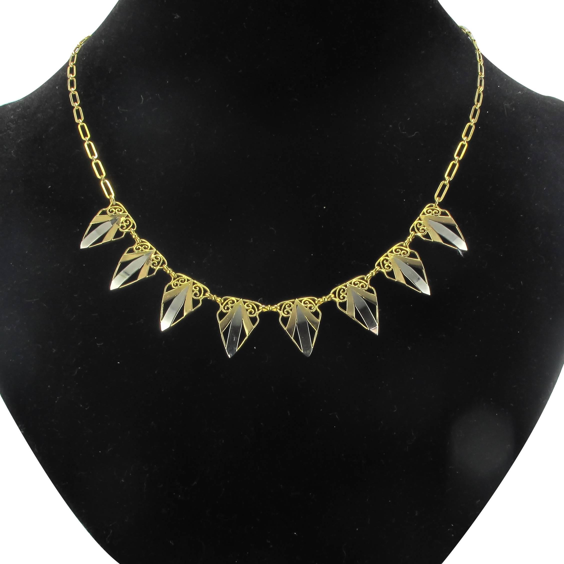 Necklace in 18 carat white and yellow golds. 
This gorgeous antique necklace is composed of 8 triangular openwork motifs in gold filigree with an arrowhead design in white gold and yellow gold. These links are connected by rectangular ‘tied’ links