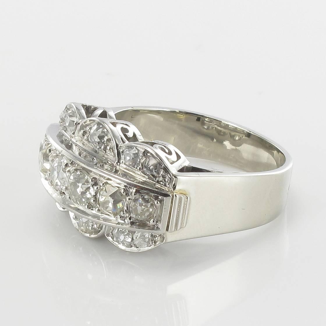 Ring in platinium and 18 carat white gold, dog and eagle heads hallmarks.

This splendid antique ring features a line of 5 antique brilliant cut diamonds surrounded by a wavy motif also set with 10 antique brilliant cut diamonds. The ring bed is