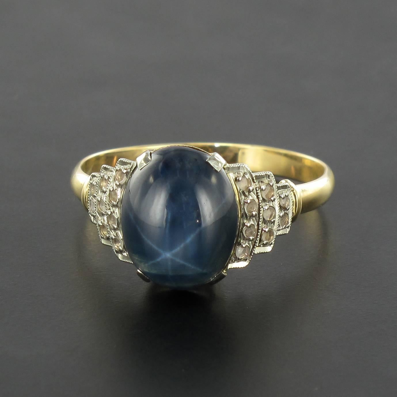 Ring in 18 Karat yellow gold, eagle head hallmark. 
This gorgeous Art Deco style ring is claw set with an oval star sapphire cabochon that is accentuated by rose cut diamonds on each side in a geometric setting. 
Weight of the sapphire: 3.31 carats