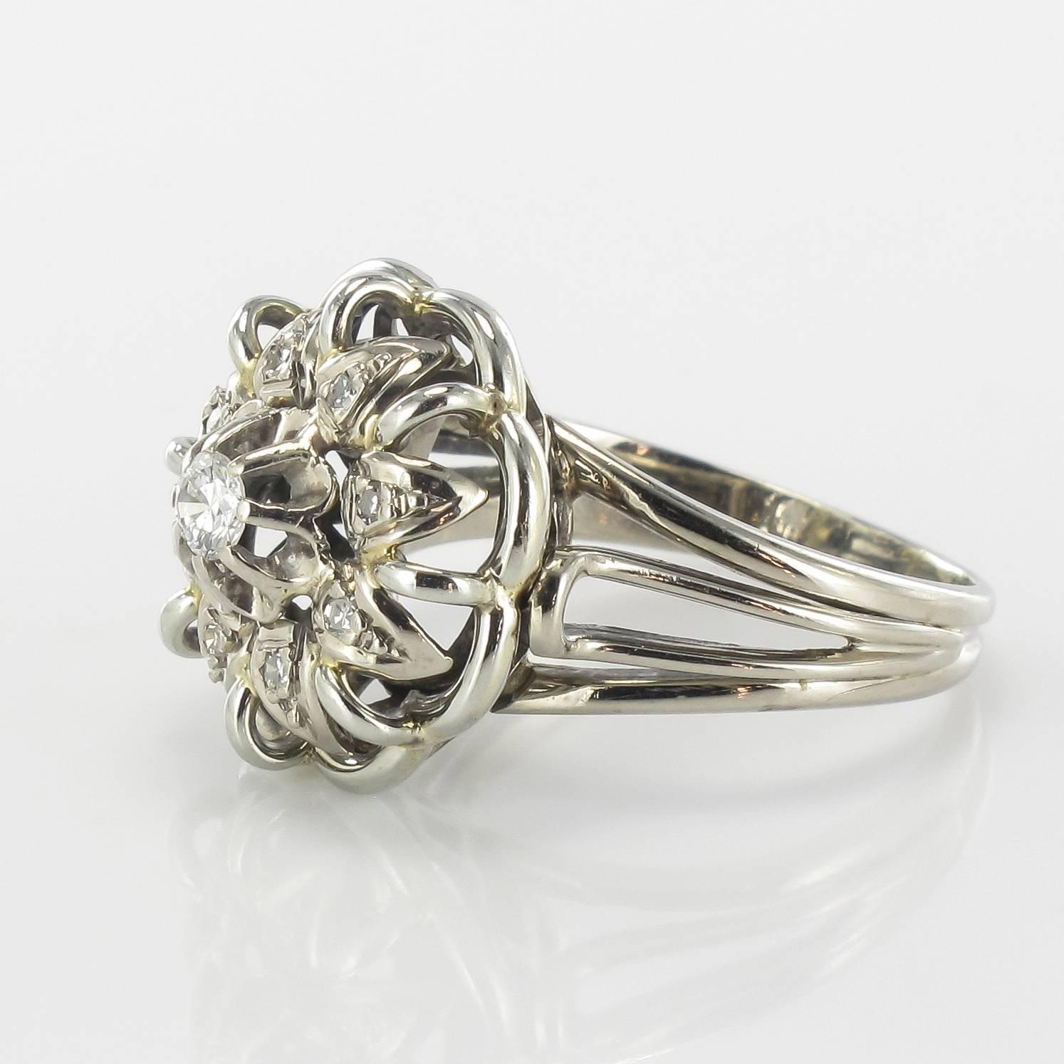 Ring in 18 carat white gold, eagle head hallmark. 

This splendid antique diamond ring features a central claw set modern brilliant cut diamond which is edged by a strand of white gold with 8 brilliant cut diamonds in a geometric pattern. The bed