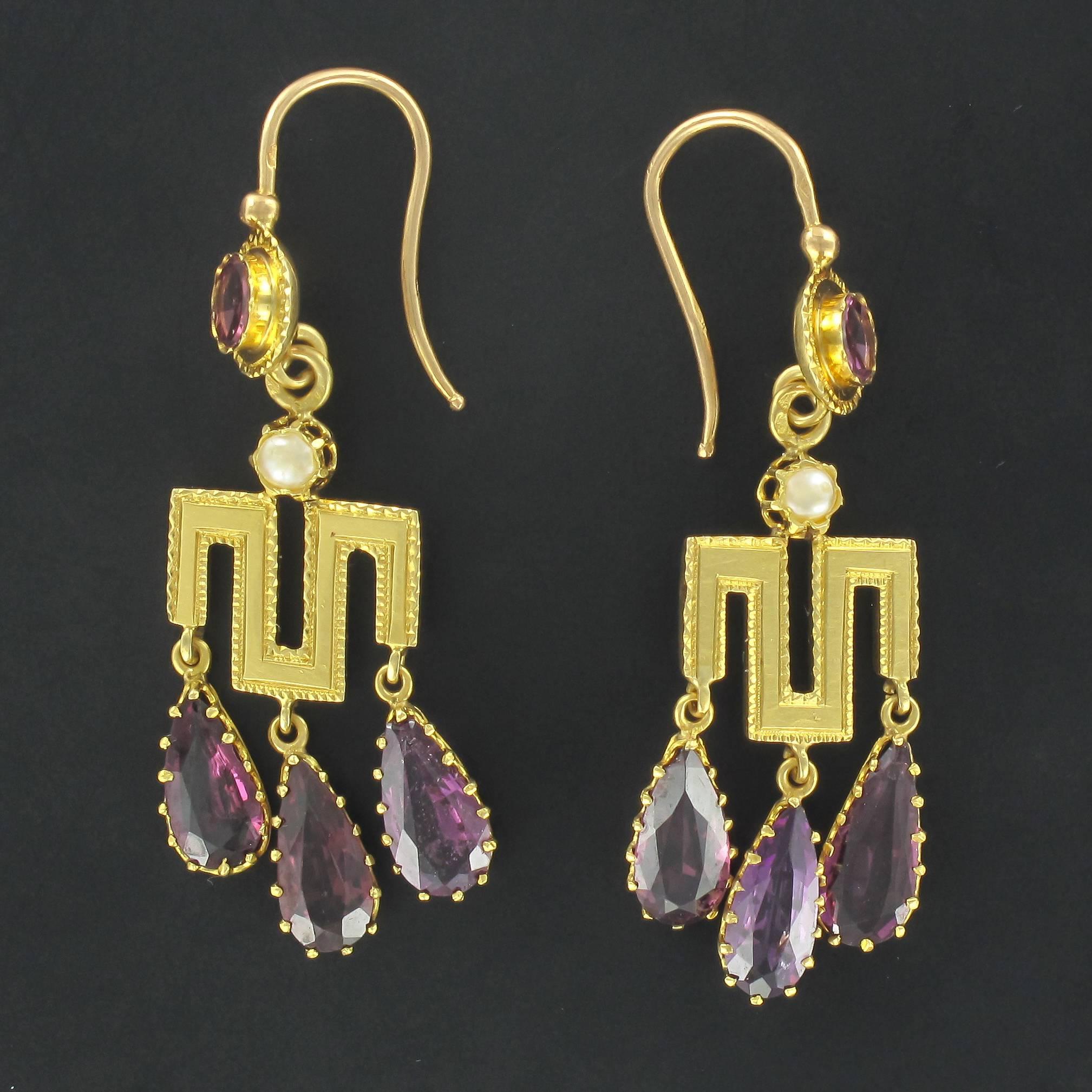 Earrings in 18 carat yellow gold, eagle head hallmark.

Each drop earring is composed of a bezel set round garnet from which is suspended a claw set fine pearl and an openwork Greek style motif with a chiselled border. 3 claw set pear cut garnets