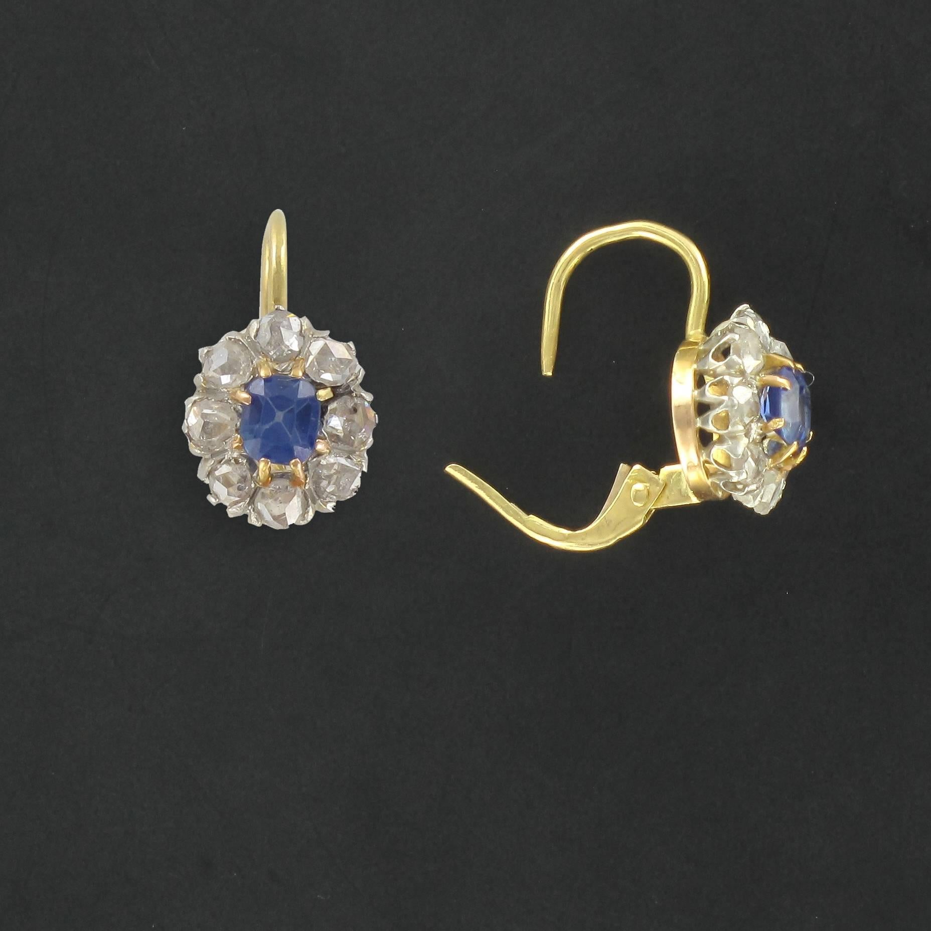 Earrings in 18 carat yellow gold. 

Each Daisy style sleeper earring is claw set with a cushion cut sapphire surrounded by antique cut diamonds. The snap clasp is at the back. 

Overall height: 1.6 cm, Width at widest: 9 mm, Thickness at widest: