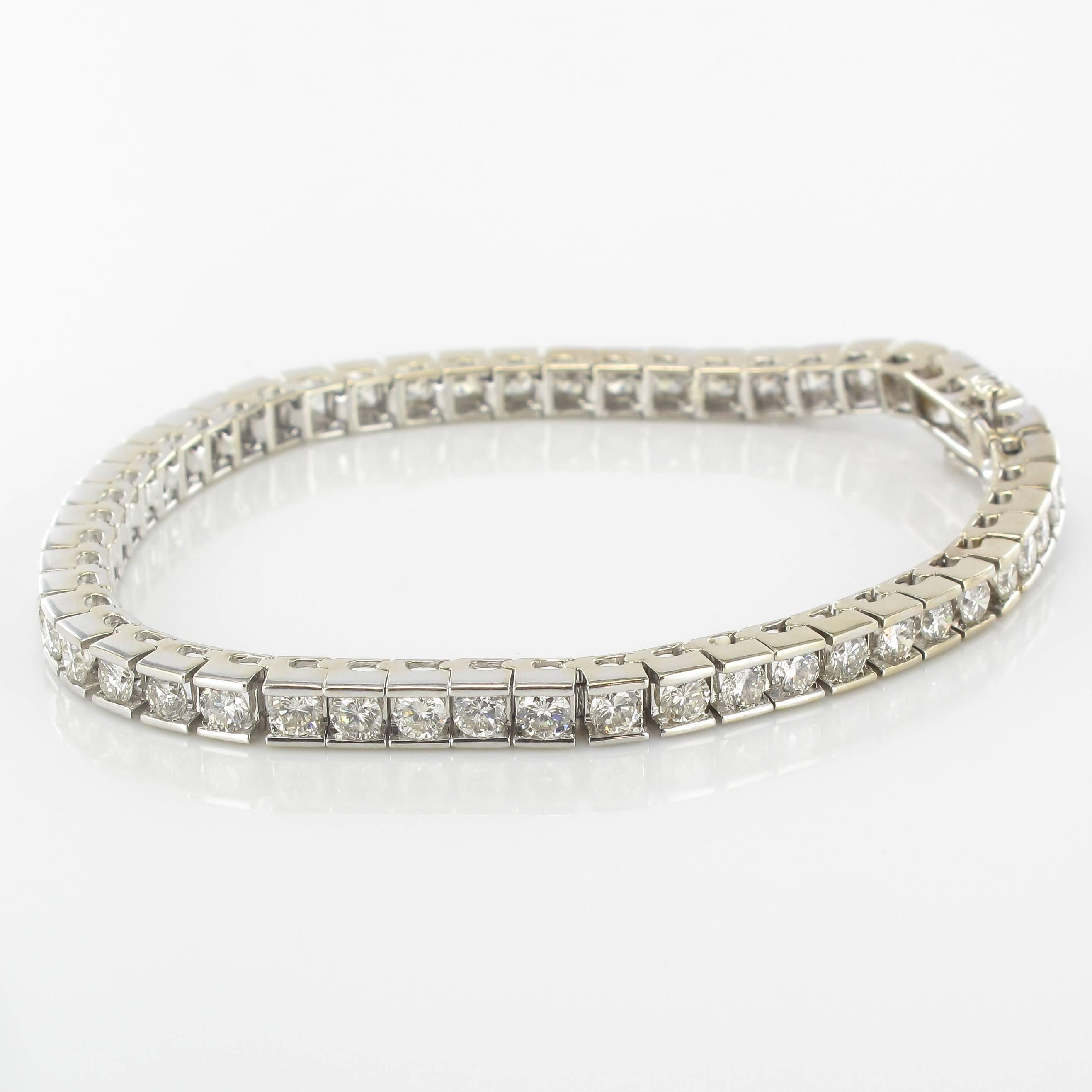 Bracelet in white gold, 585 thousandths, 14 carats.
This strap bracelet is composed of articulated square links each set with a modern brilliant cut diamond. The clasp is in the form of a ratchet with a safety 8 feature. 
A radiant white gold and