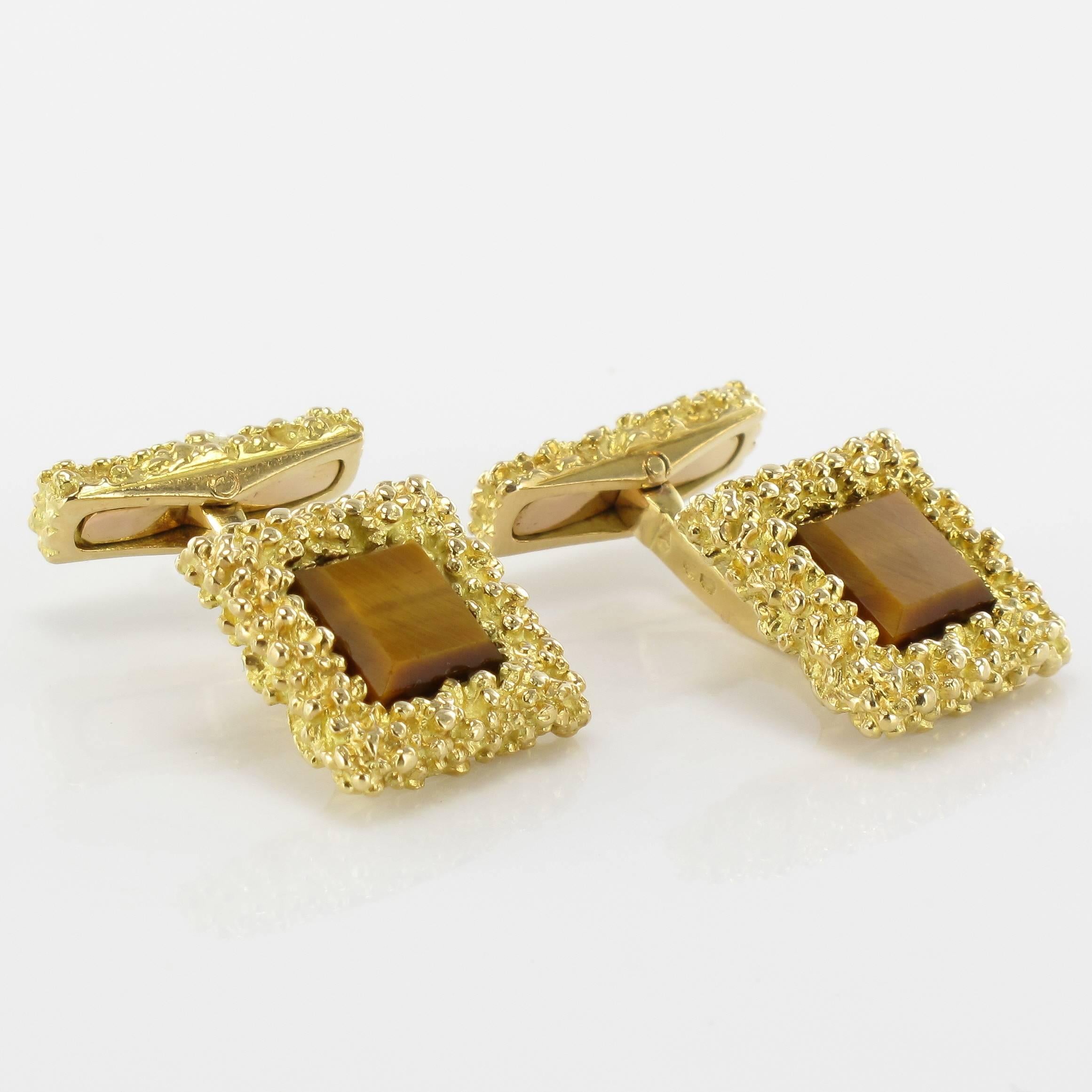 Cufflinks in 18 carat yellow gold. 

Each splendid square cufflink features a textured motif of gold beads set around a square tiger’s eye quartz. The bar also features this textured gold. 

Dimension of the square motif: 1.5 cm side, Thickness 5