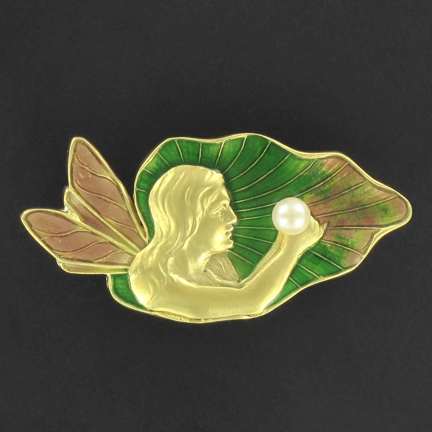 18 carat yellow gold brooch, eagle head hallmark. 

This splendid gold Art Nouveau style brooch displays the face and bust of a fairy with loose hair and unfolded wings holding a cultured round oriental white pearl in her hands. Apart from the fairy