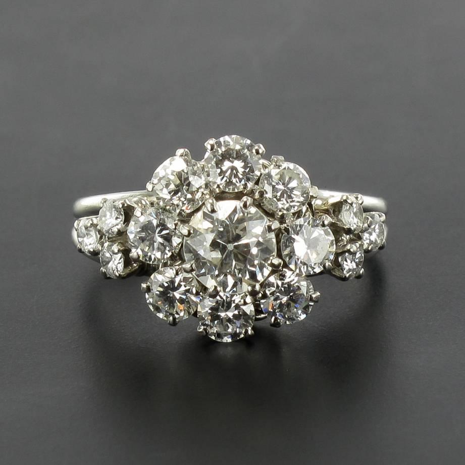 Platinum ring, french dog's head hallmark.

This gorgeous antique Daisy style ring is claw set with a brilliant cut diamond surrounded by 8 other brilliant cut diamonds. On each side, on the beginning of the ring band, are 3 other claw set brilliant