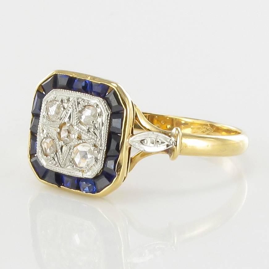Yellow gold and white gold ring, 18 carats, eagle head hallmark.

This square shaped antique ring is set with 5 rose cut diamonds in an openwork star themed motif that is surrounded by calibrated blue gems. On each side, at the beginning of the ring